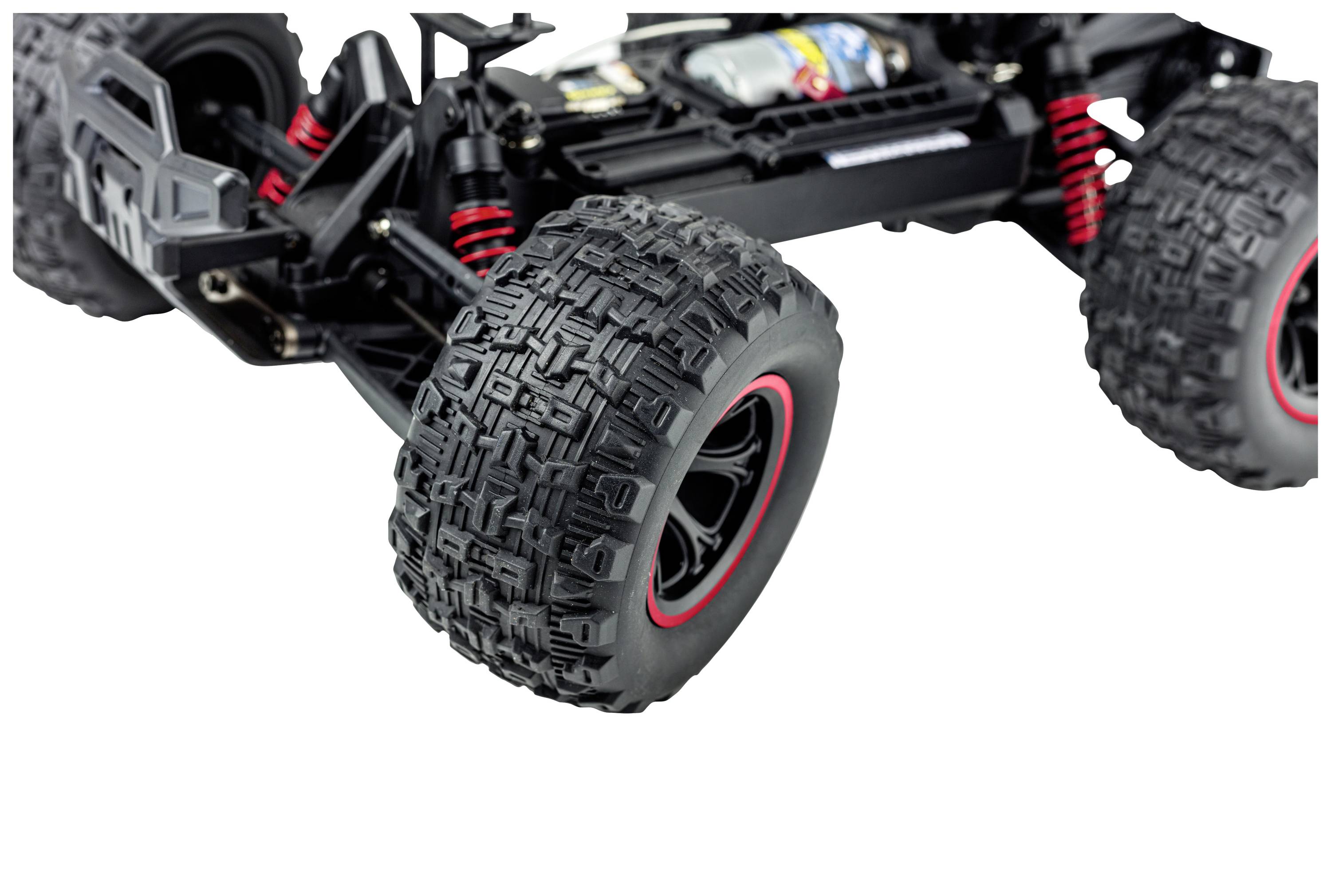 Nahaufnahme eines ferngesteuerten Autos; Fokus auf die robusten, schwarz-roten Offroad-Reifen und die Federung.