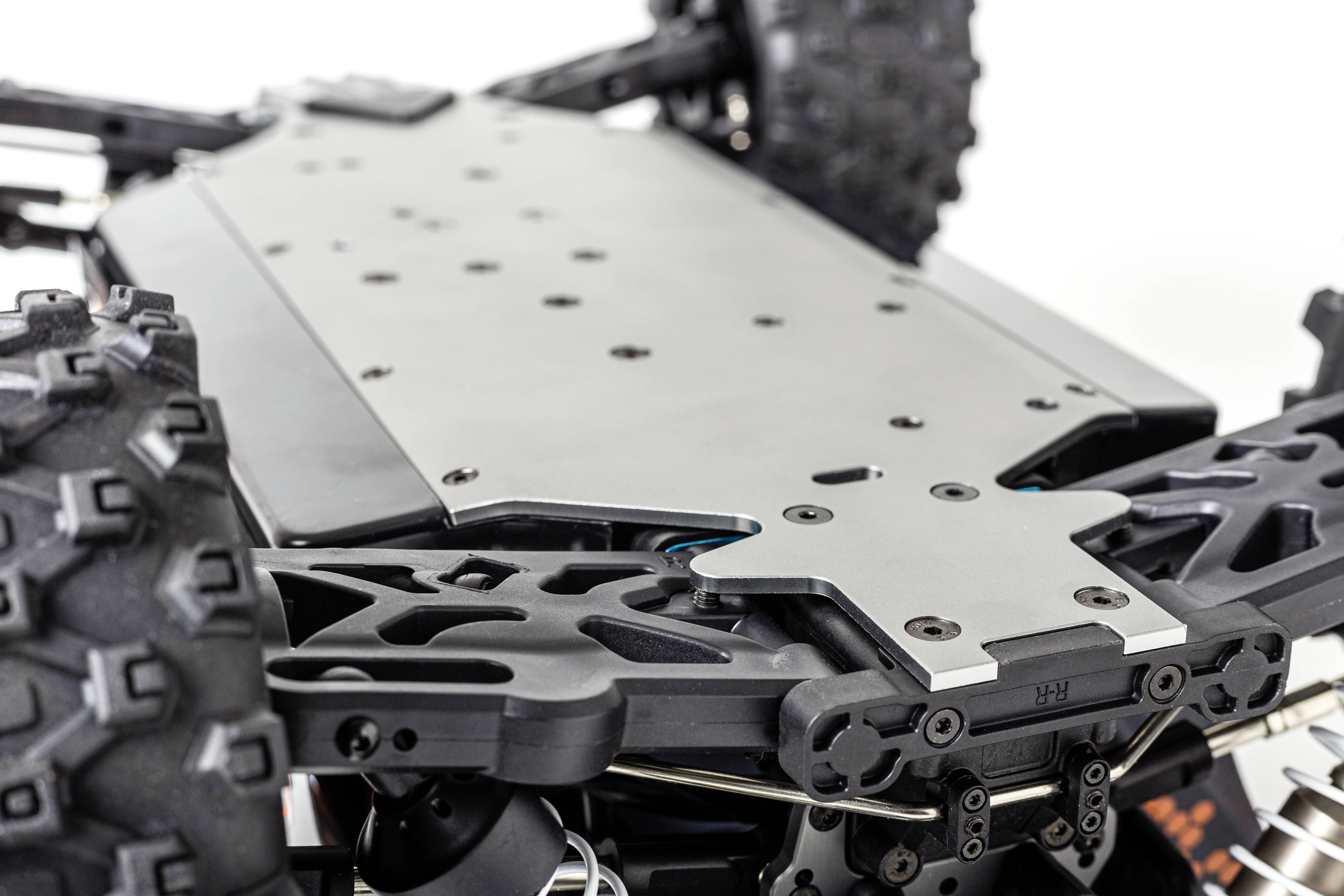 Nahaufnahme eines ferngesteuerten Modellautos, die den Unterboden zeigt. Sichtbar sind robuste Reifen und mechanische Details des Fahrwerks.