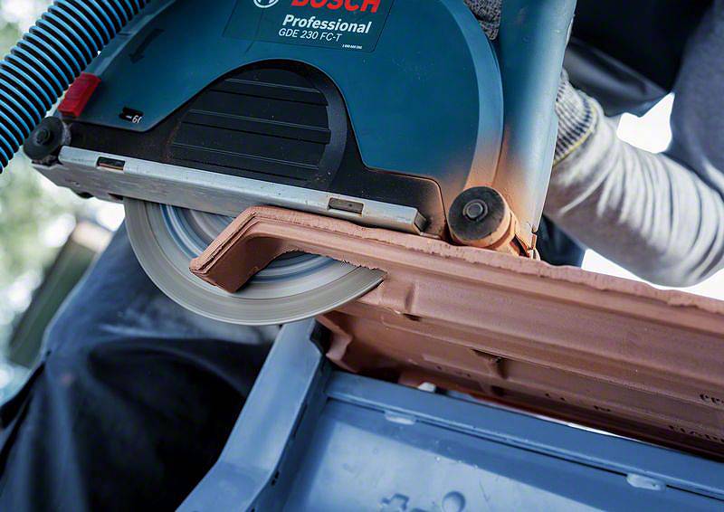 Eine Person schneidet ein Dachziegel mit einer elektrischen Säge der Marke Bosch. Der Fokus liegt auf der Schneideaktion und dem Werkzeug.