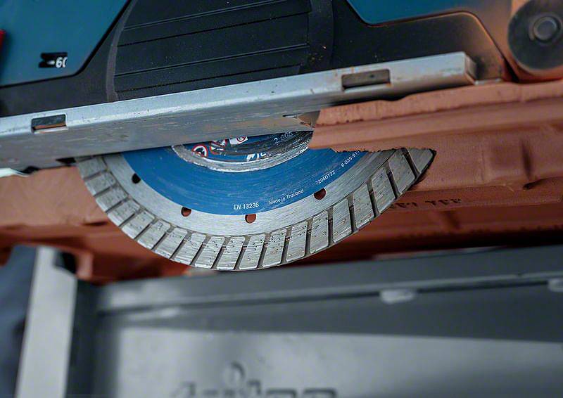 Eine Kreissäge mit einem blauen und silbernen Sägeblatt, teilweise eingezogen in einem Gehäuse. Sie scheint zum Schneiden bereit.