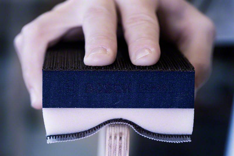 Nahaufnahme einer Hand, die einen Tischtennisschläger hält. Der Fokus liegt auf der Oberfläche des Schlägers und den Fingerspitzen.