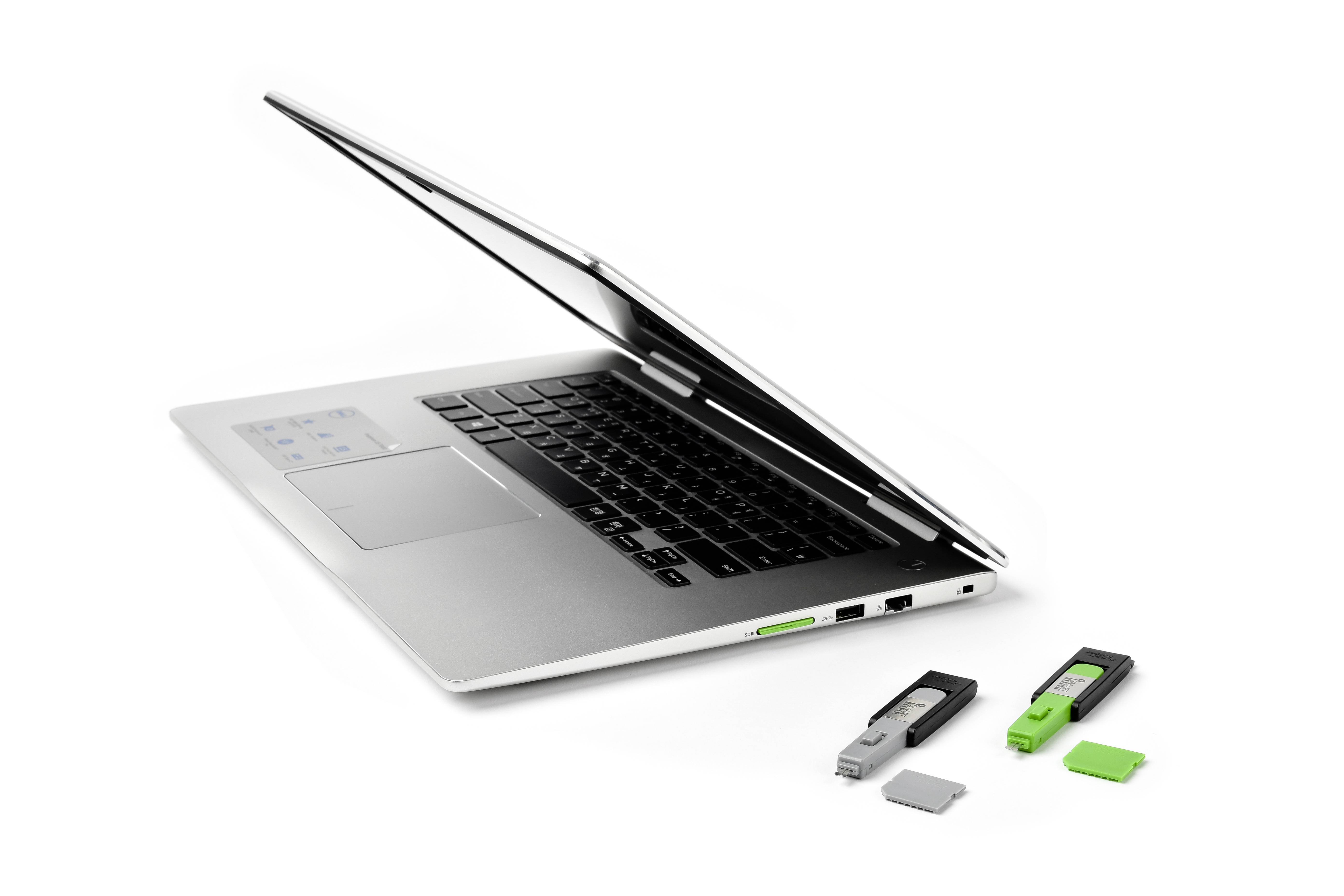 Silberner Laptop mit leicht aufgeklapptem Bildschirm, daneben drei USB-Sticks in Schwarz und Grün sowie eine Speicherkarte.