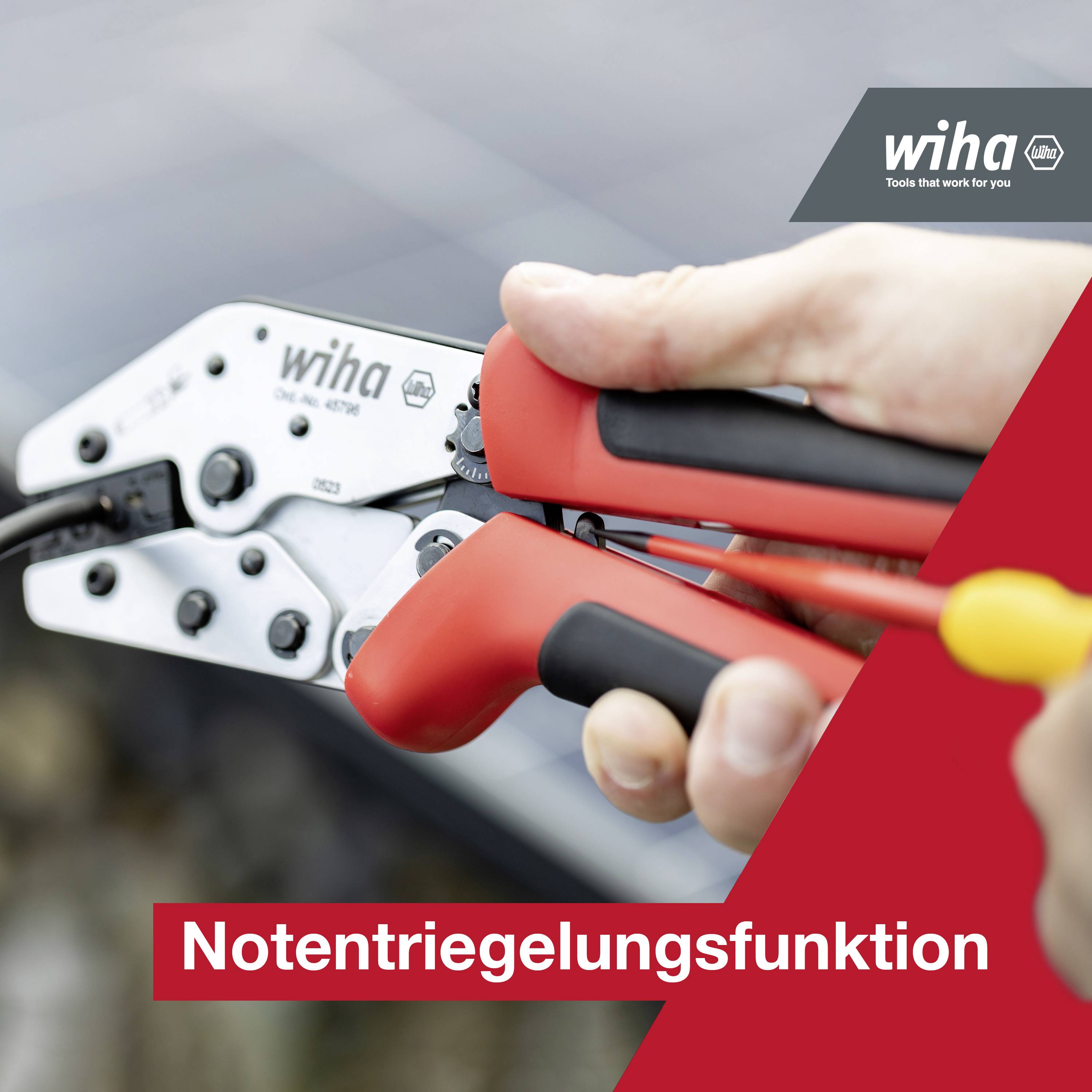 Hand hält einen roten Wiha Seitenschneider mit Notentriegelungsfunktion. Hintergrund leicht unscharf, Fokus auf Werkzeug und Hand.