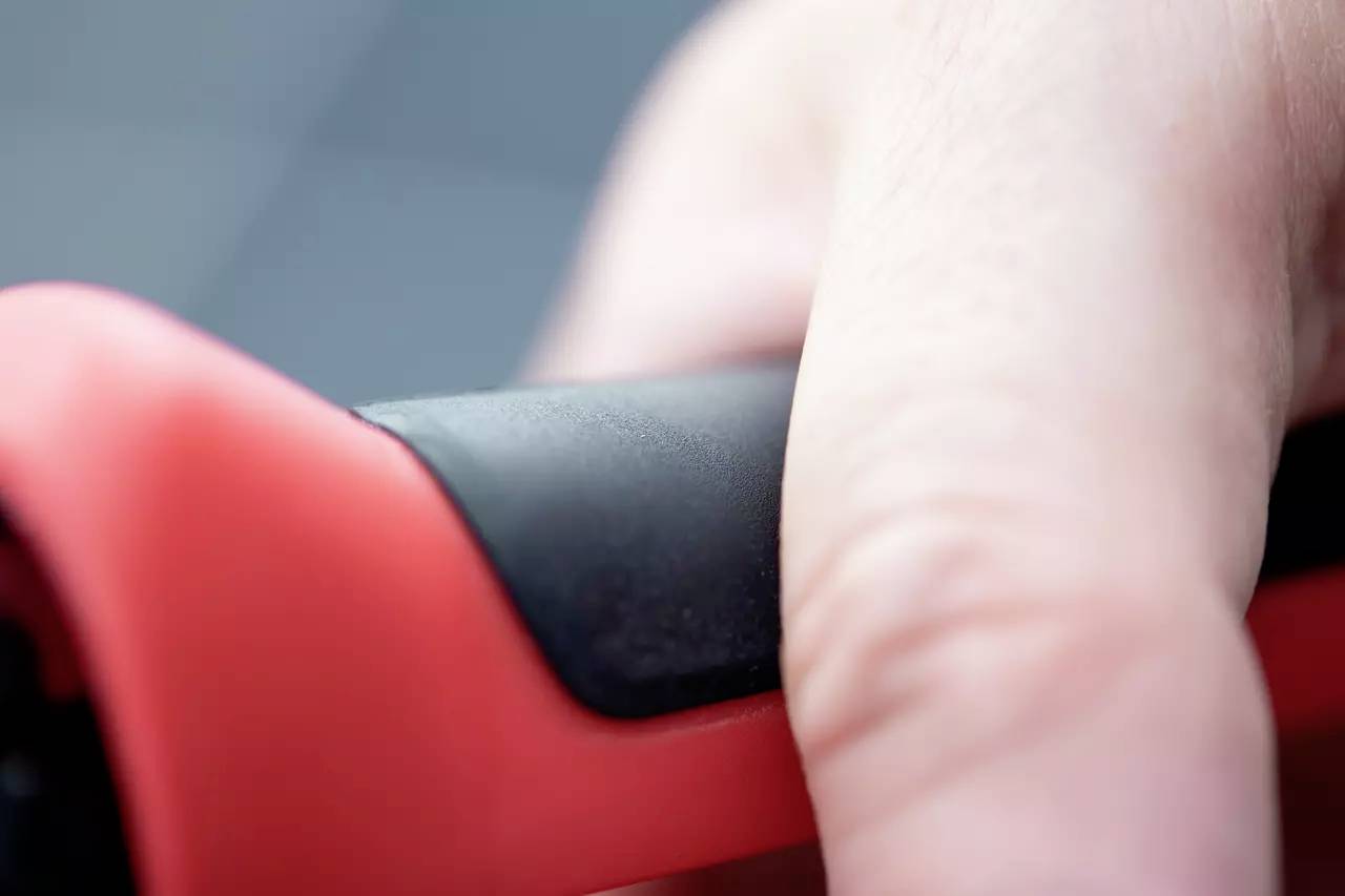 Nahaufnahme eines Fingers, der einen rot-schwarzen Griff hält.
