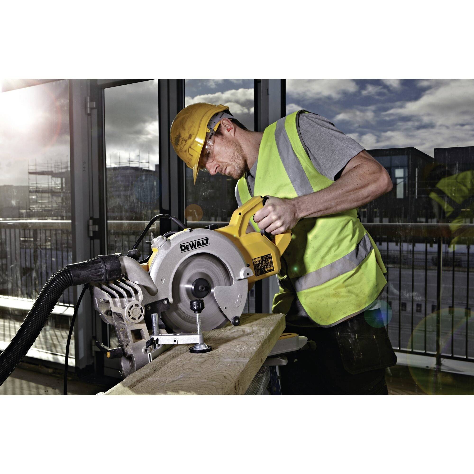 Ein Bauarbeiter mit Schutzhelm und Weste benutzt eine elektrische Sägemaschine, um ein Holzbrett zu schneiden.
