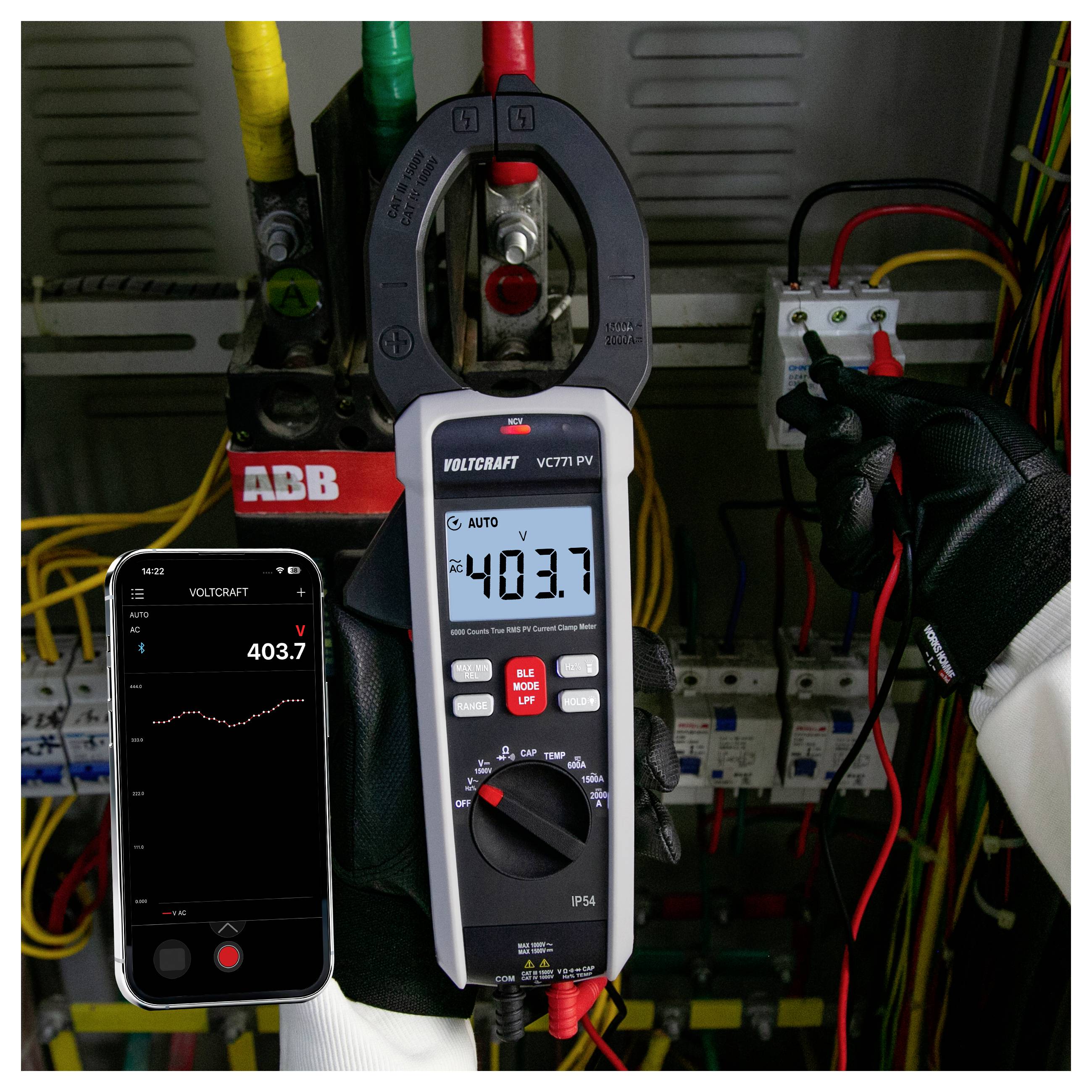 Ein Techniker misst elektrische Spannung in einem Schaltschrank mit einem Zangenmessgerät und einem Smartphone, wobei beide ungefähr 403,7 V anzeigen.