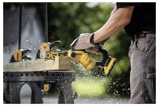 Eine Person, die mit einer Kreissäge ein Holzbrett auf einer Werkbank im Freien sägt, wobei Sägespäne umherfliegen, während die Säge durch das Holz schneidet.