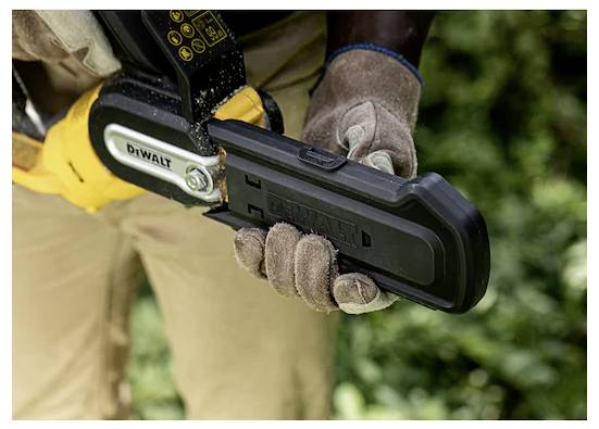 Eine Person mit Handschuhen hält eine Motorsäge mit einer Hand und konzentriert sich auf den Griff und den Bereich der Klinge. Der Hintergrund zeigt verschwommenes Grün.