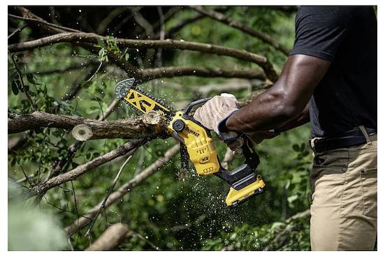 Eine Person, die eine gelbe Kettensäge verwendet, um einen Baumast in einer Außenumgebung zu schneiden, umgeben von grünem Laub.