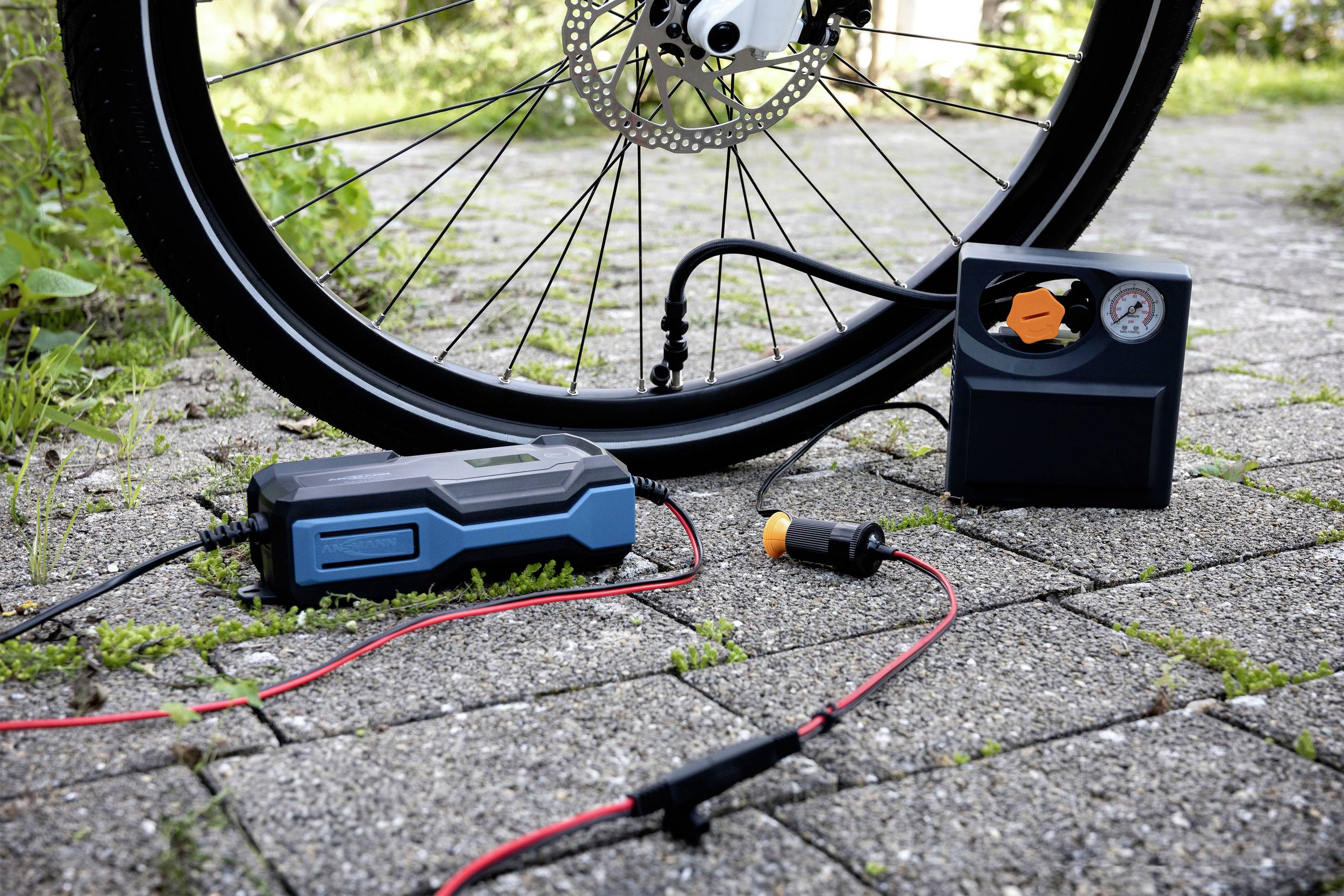 Ein Fahrradreifen wird auf einem gepflasterten Weg mit einer tragbaren Luftpumpe aufgepumpt.