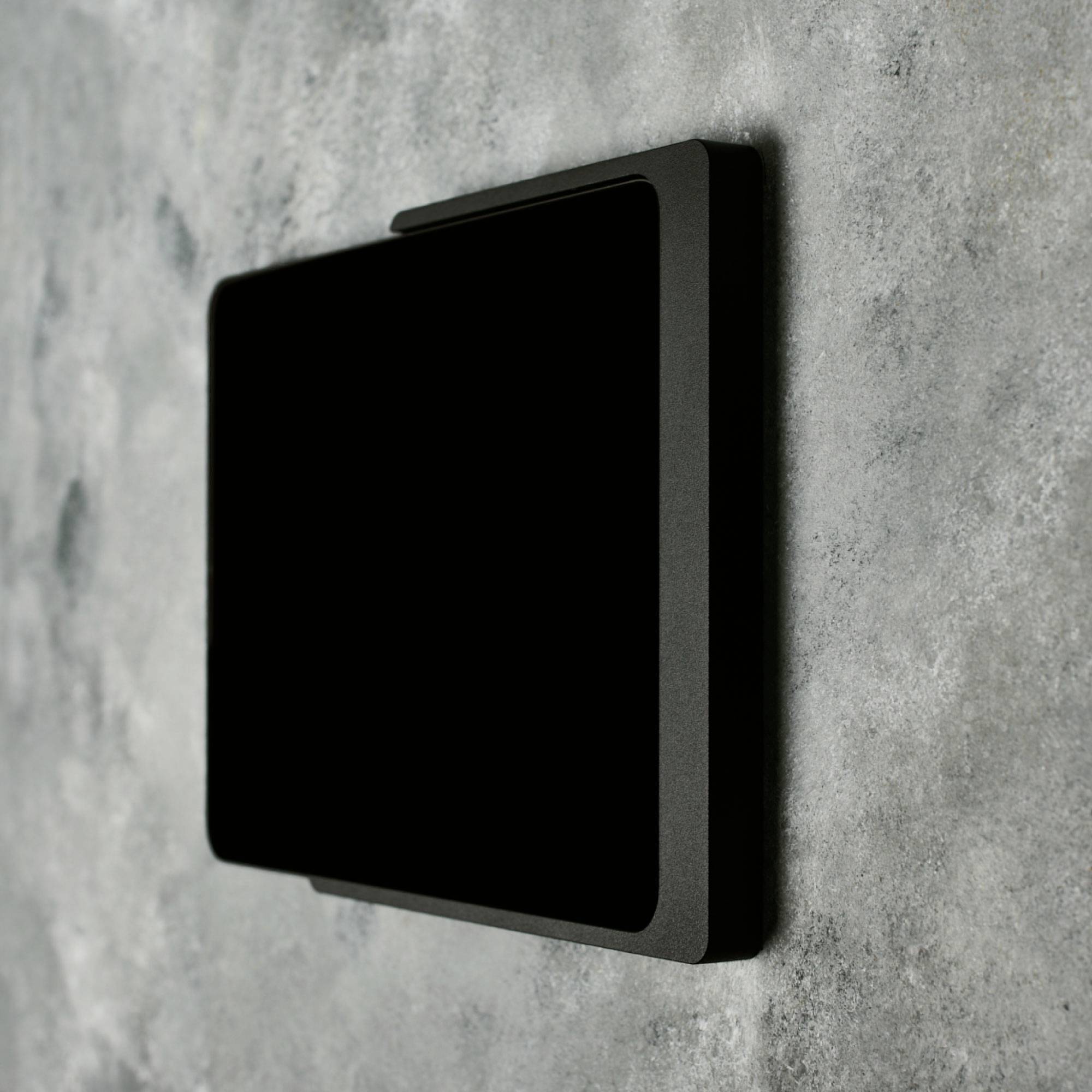 An der Wand ist ein rechteckiger, schwarzer Lichtschalter zu sehen.