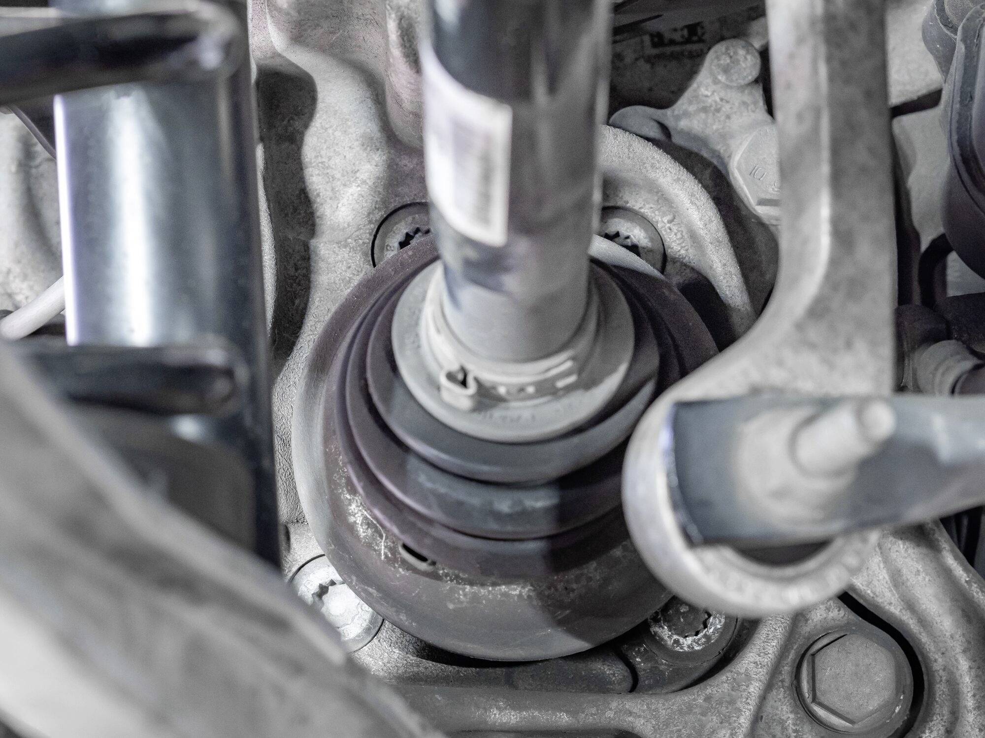 Nahaufnahme eines Stoßdämpfers und Aufhängungsteils eines Autos, zeigt Federungskomponenten in grauen und metallischen Farbtönen.