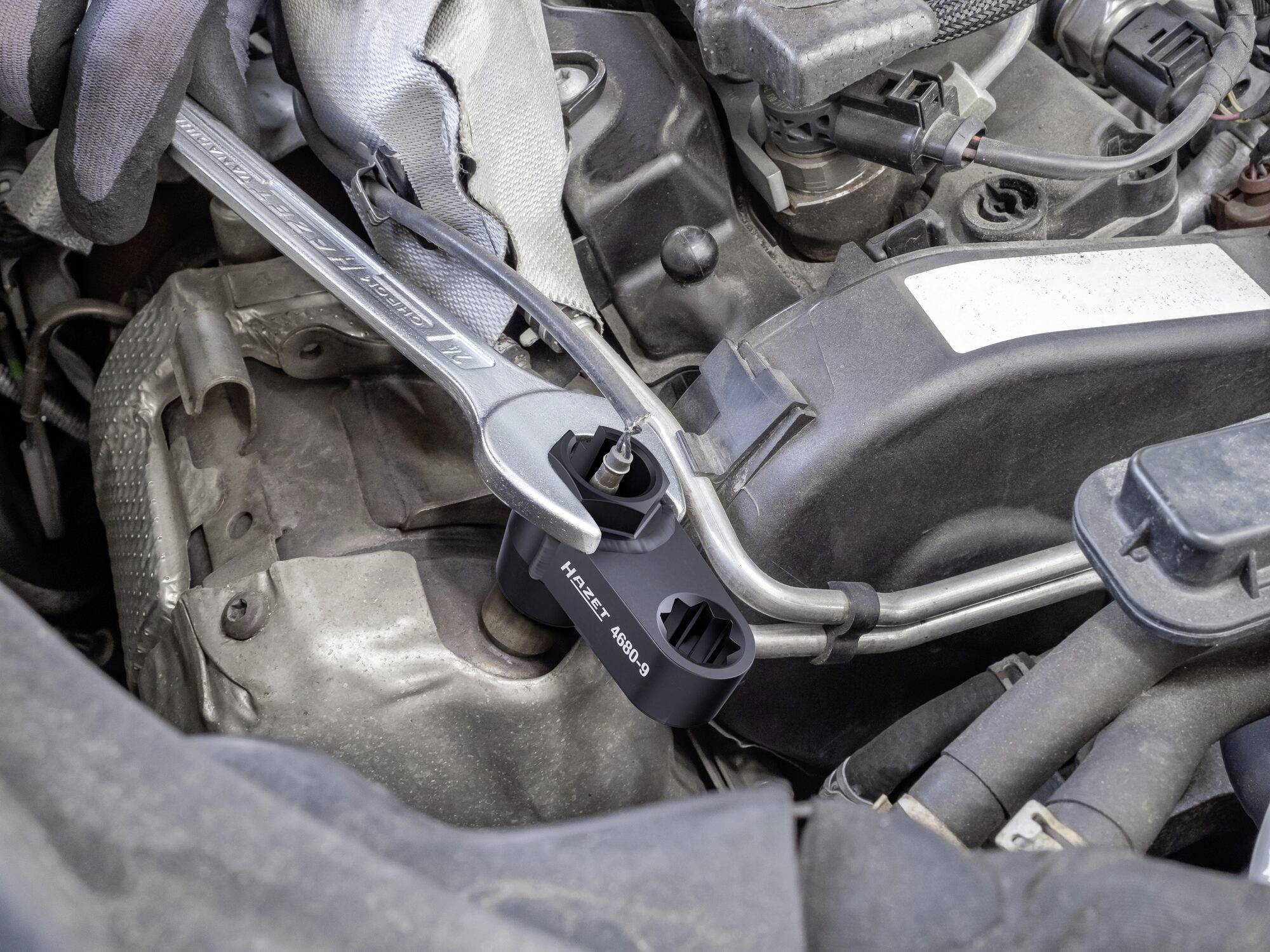 Ein Drehmomentschlüssel wird zum Anziehen einer Mutter am Motor eines Autos benutzt. Ein spezieller Adapter ist aufgesteckt.