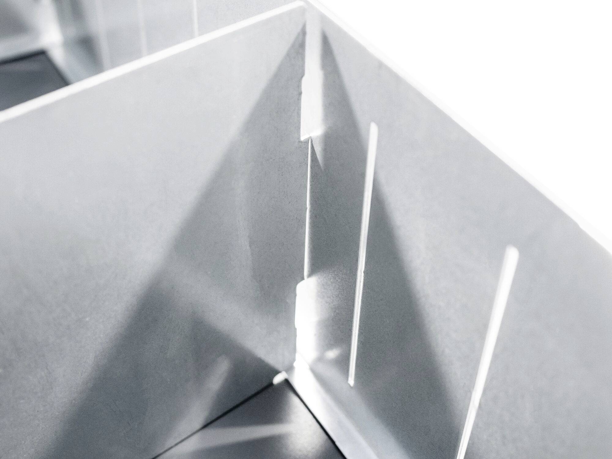 Nahaufnahme eines Metallecks mit mehreren senkrechten und waagerechten Schlitzen, die in präzisen Winkeln geschnitten sind.