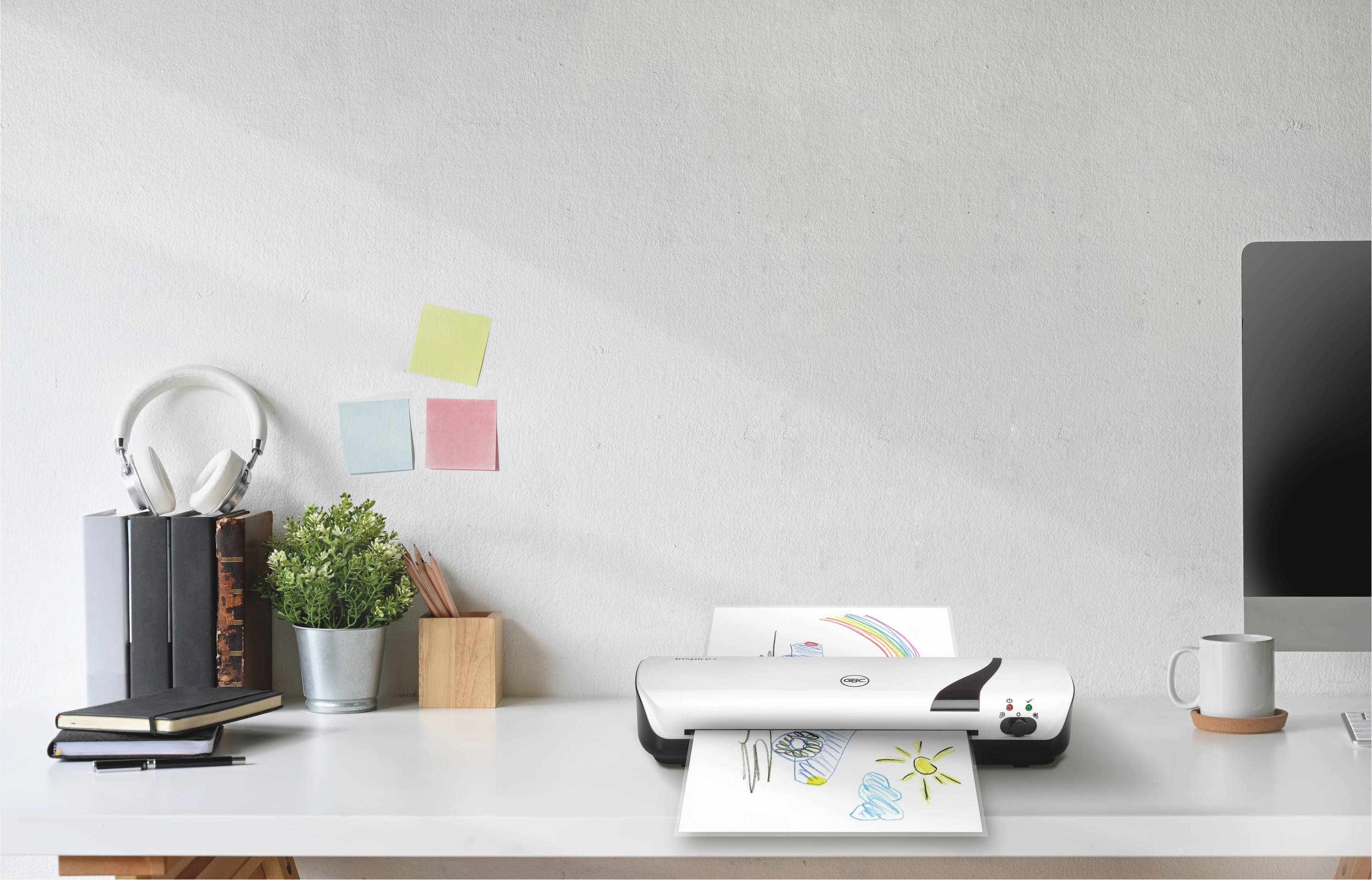 Ein Schreibtisch mit einem Scanner, der eine Zeichnung von Sonne und Wolken scannt. Pflanzen, Bücher und Kopfhörer sind daneben platziert.