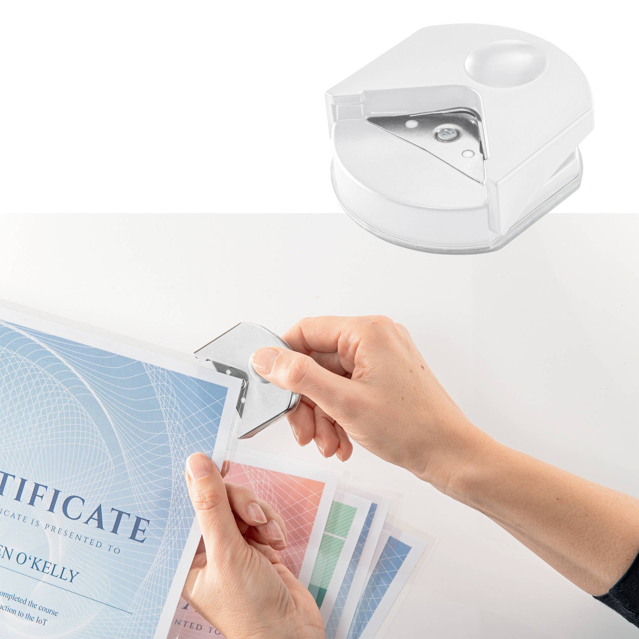 Eine Person verwendet ein rundes Stanzgerät, um die Ecken von Zertifikaten abzurunden.