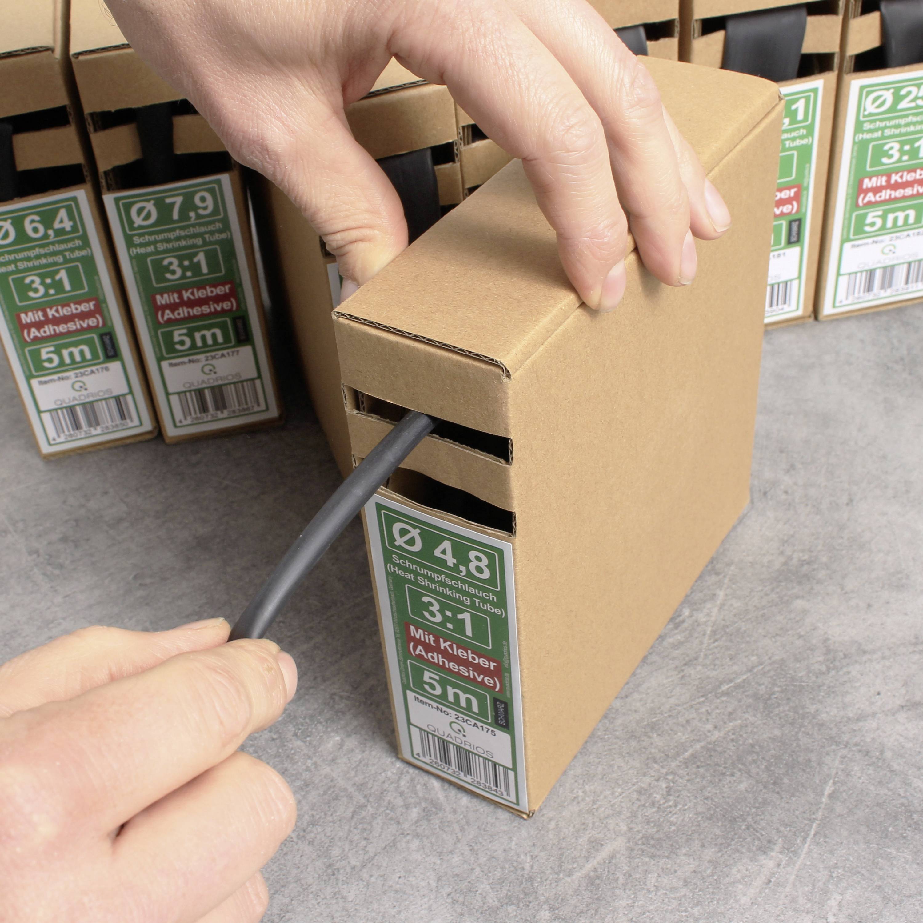 Eine Hand zieht ein schwarzes Kabel aus einer Kartonverpackung mit der Aufschrift 'Ø 4,8 3:1 Mit Kleber (Adhesive) 5 m'.