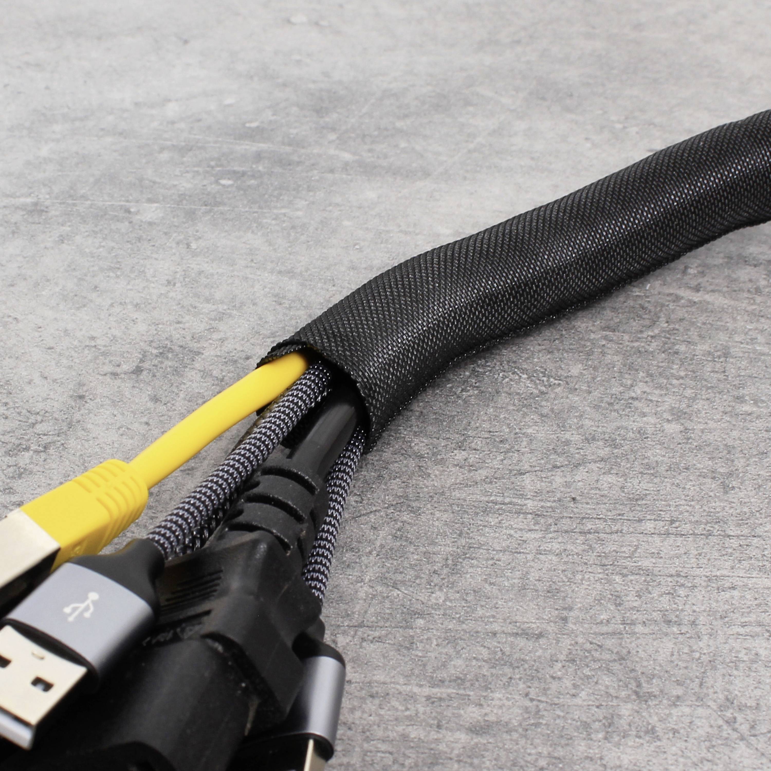 Ein Bündel von elektrischen Kabeln, darunter ein grauer HDMI- und ein gelber USB-Stecker, ist in einem schwarzen Kabelschlauch organisiert.