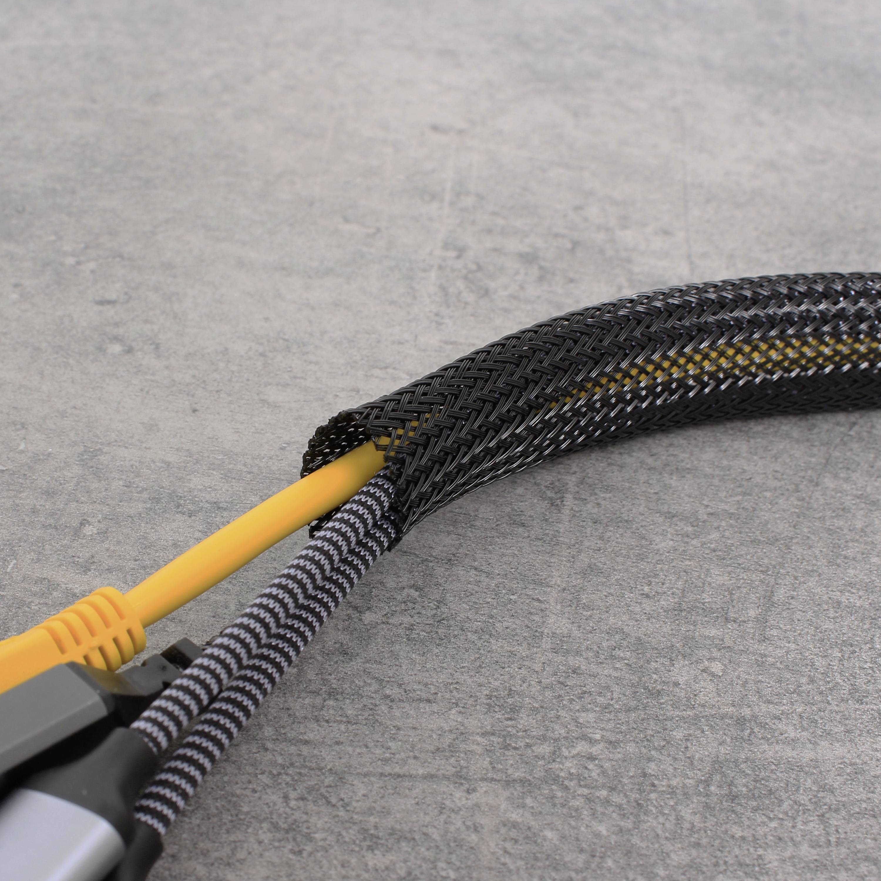 Ein gelbes und ein schwarzes Kabel sind mit einem schwarzen geflochtenen Kabelschutz ummantelt, auf grauem Hintergrund.