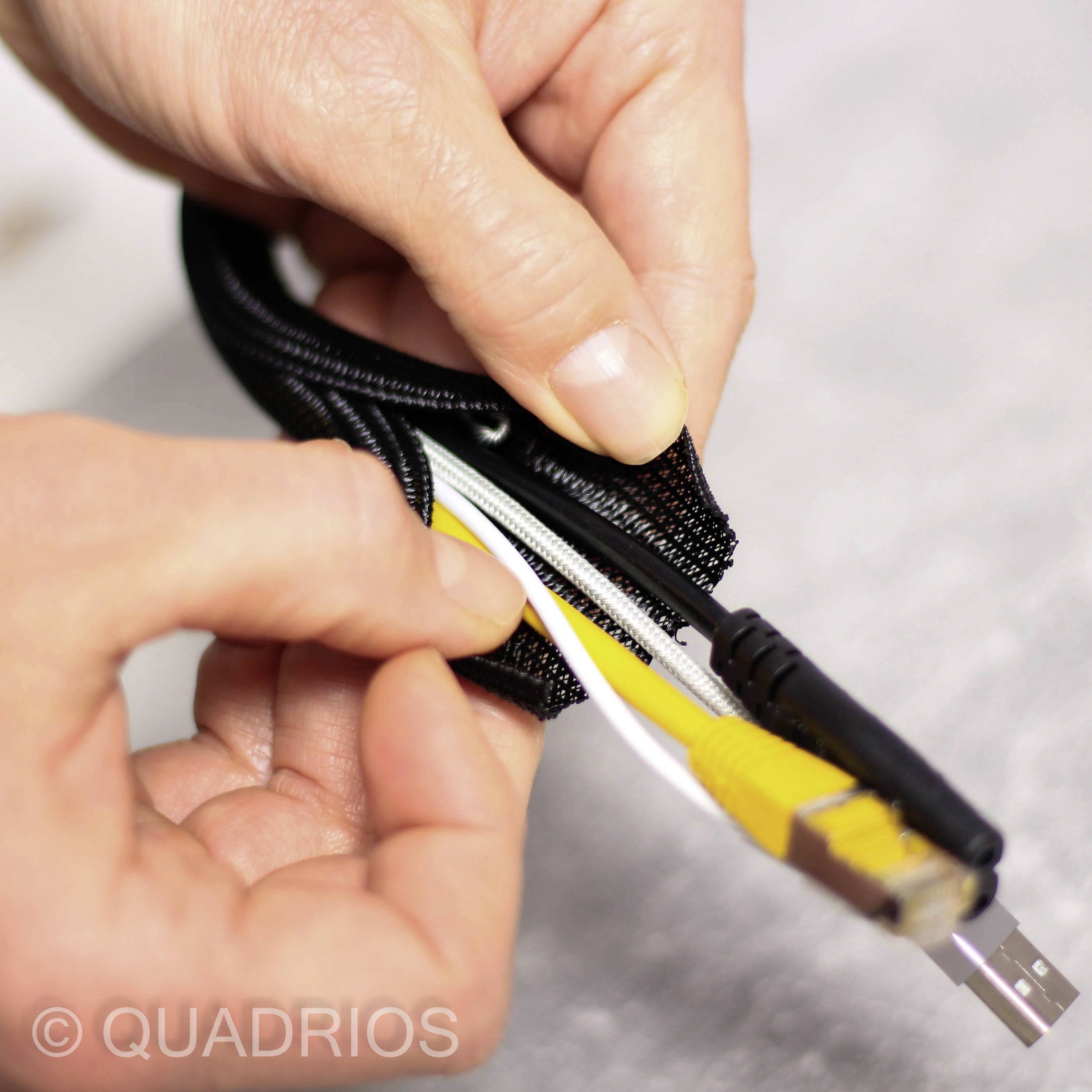 Eine Hand zeigt, wie mehrere Kabel mit einer schwarzen Kabelhülle gebündelt werden. Sichtbar sind USB- und Ethernet-Kabel.