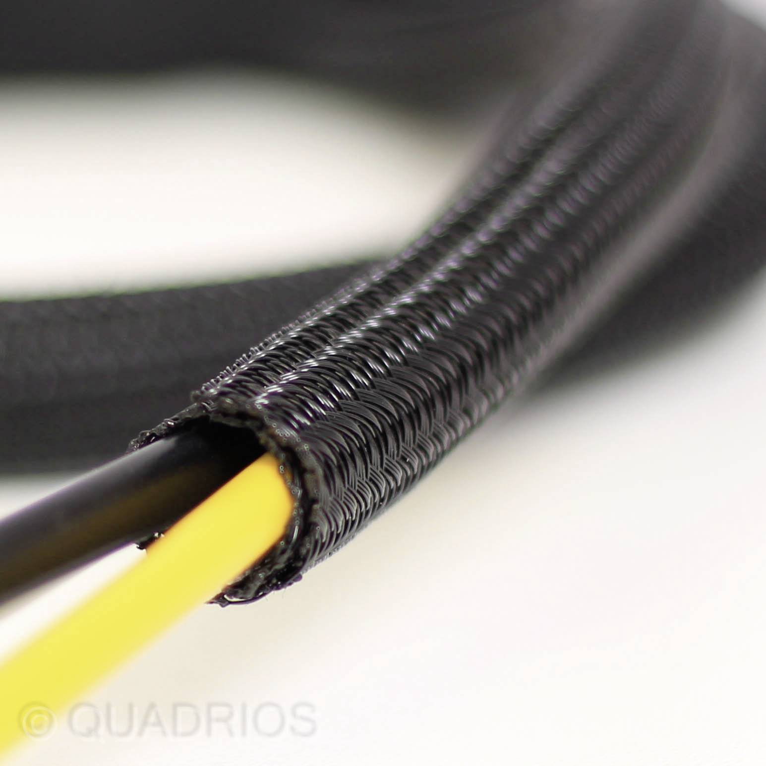 Ein schwarzes geflochtenes Kabel umschließt zwei dünne, gelbe und schwarze Kabel. Im Hintergrund verschwommen.