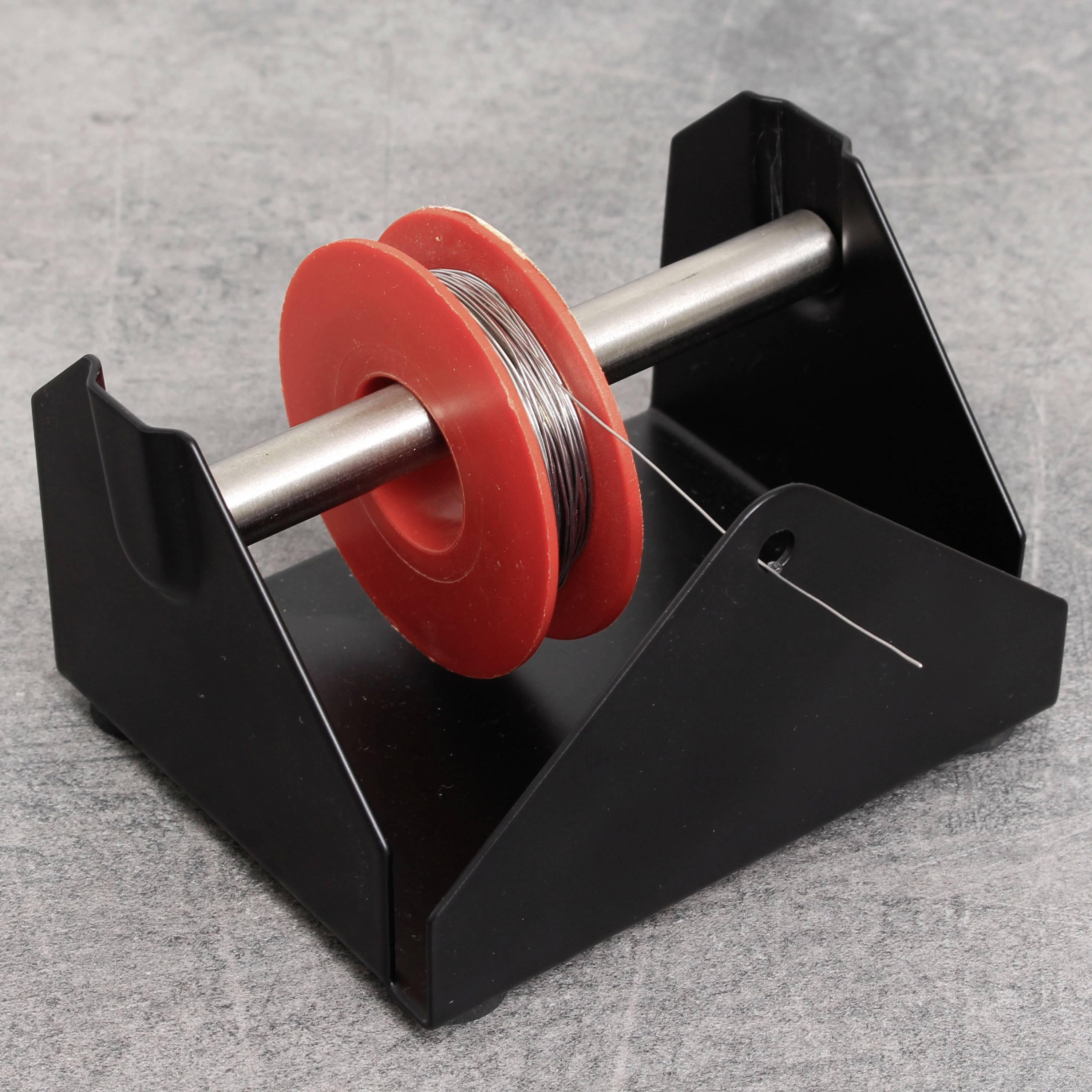 Eine rote Spule mit schwarzem Draht auf einem schwarzen Halter.