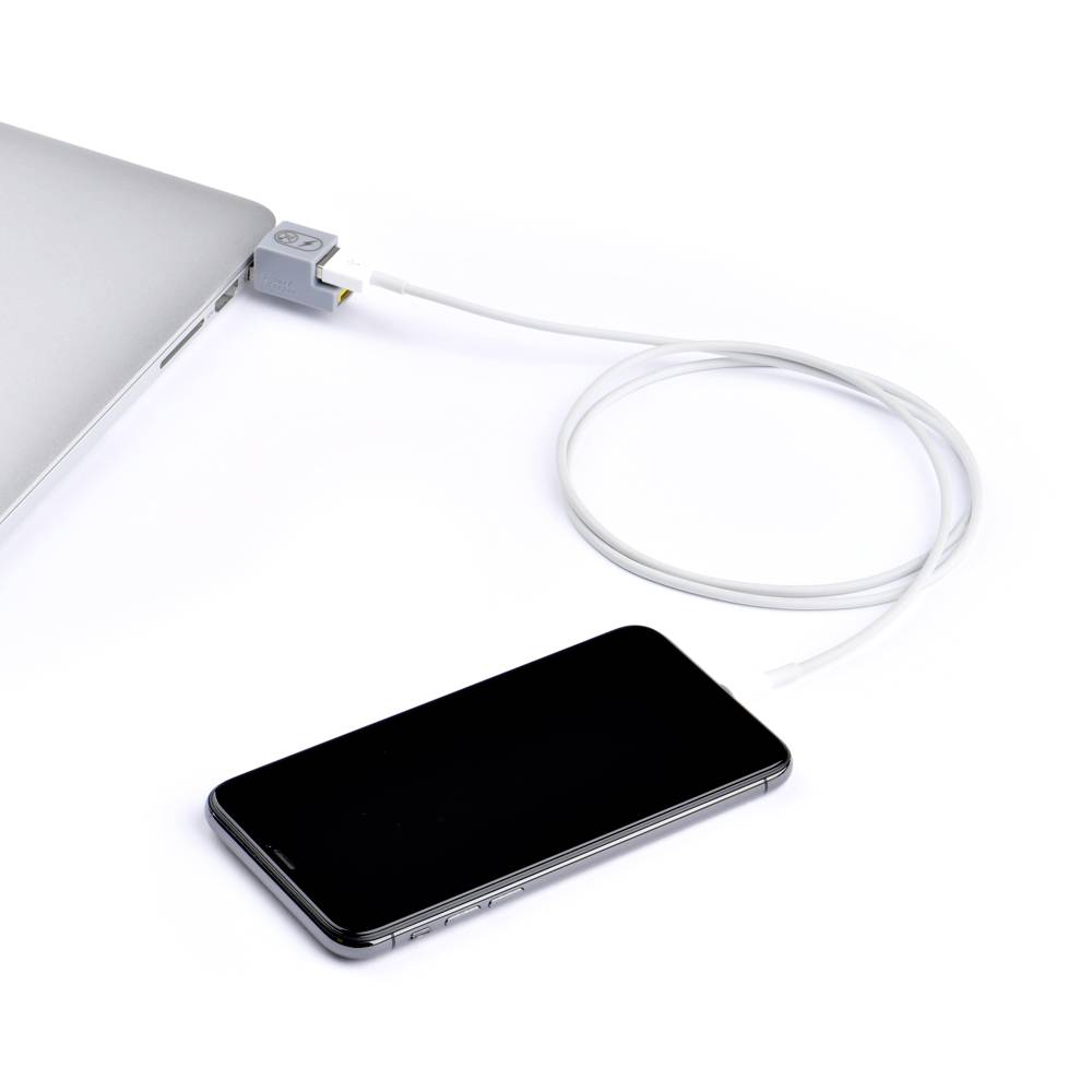 Ein Smartphone liegt neben einem Laptop, verbunden durch ein USB-Kabel.