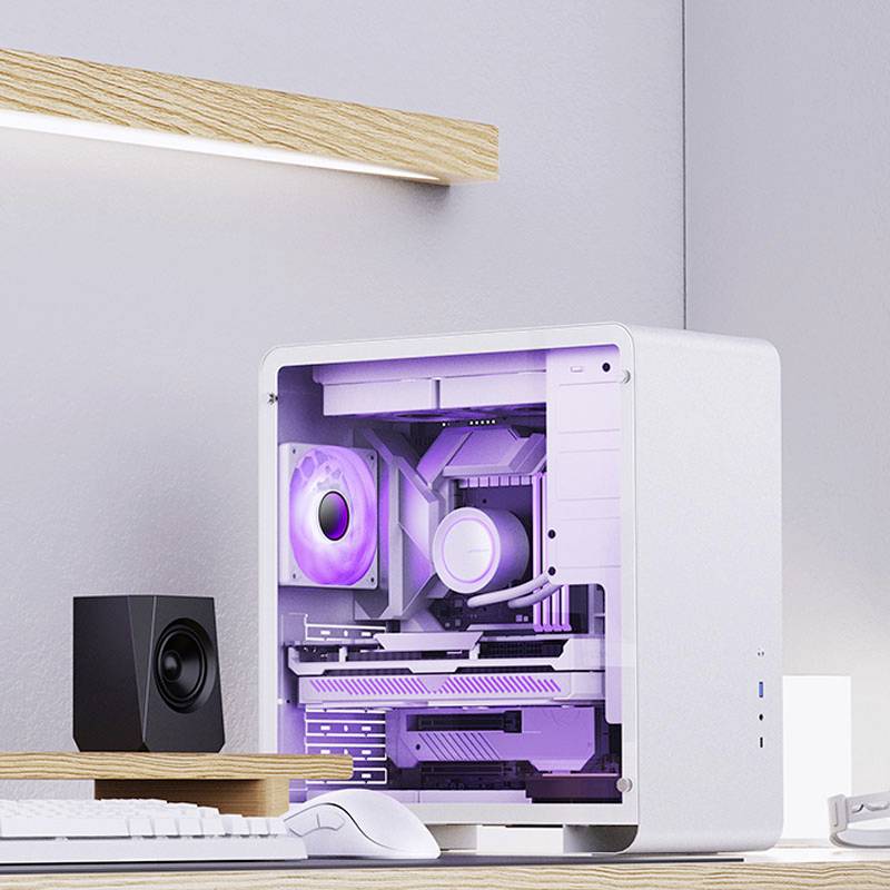 Ein weißer Computer mit lila LED-Beleuchtung steht auf einem Schreibtisch. Daneben befinden sich ein Lautsprecher und ein Lampenregal.