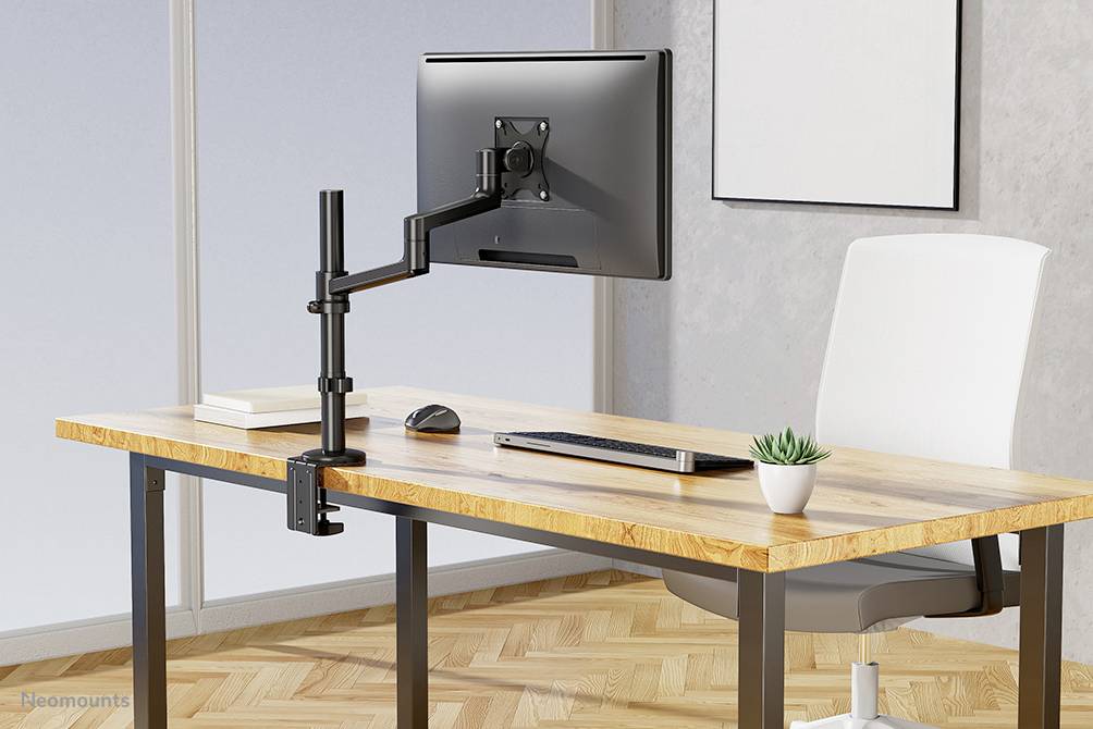 Ein Schreibtisch mit einem Computerbildschirm an einem verstellbaren Monitorarm, einer Tastatur, einer Maus und einer kleinen Pflanze.