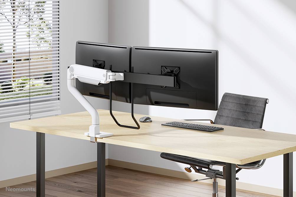 Zwei große Monitore an einem Doppelarmhalter montiert, auf einem modernen Schreibtisch mit Tastatur und ergonomischem Stuhl im Büro.