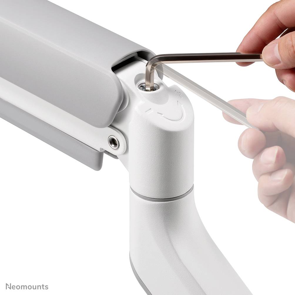 Hand justiert die Neigung eines grauen Monitorarms mit einem Schraubendreher. Der Arm ist minimalistisch gestaltet.