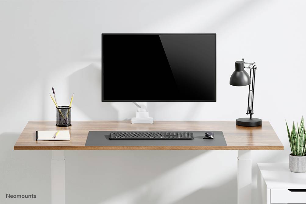 Ein Schreibtisch mit Monitor, Tastatur, Lampe und Stifthalter. Modernes und minimalistisches Design.