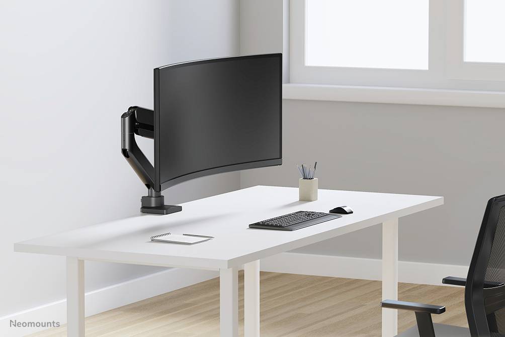 Ein moderner, minimalistischer Schreibtisch mit einem gebogenen Monitor auf einem verstellbaren Arm, Tastatur, Stiftbecher und Bürostuhl.
