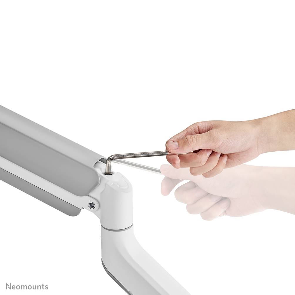 Eine Hand justiert mit einem Inbusschlüssel die Federung eines Monitorarms.