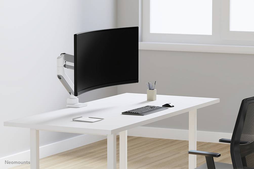 Ein schlichtes, modernes Büro mit einem weißen Tisch, darauf ein gebogener Monitor am Halter, eine Tastatur, Maus und Stiftehalter.