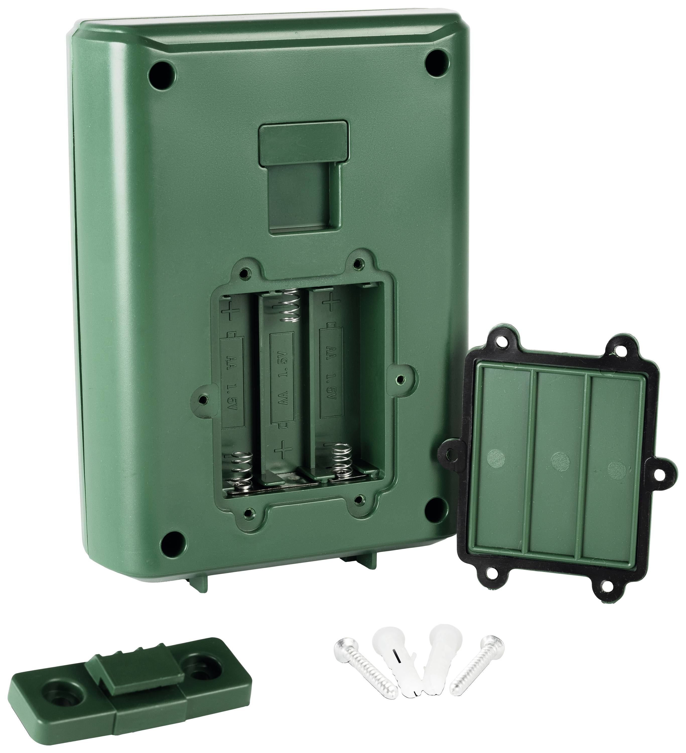 Grünes Batteriefachgehäuse mit abgenommenem Deckel, sichtbar sind Steckplätze für Batterien. Schrauben und Wandhalterung daneben.
