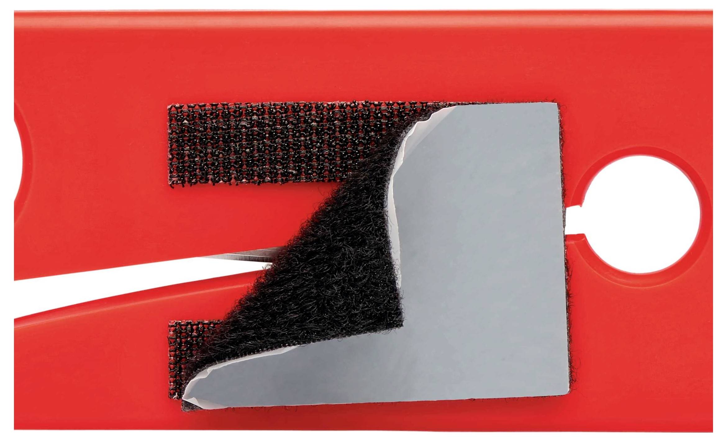 Ein roter Gegenstand mit einem Klettverschluss und einer metallischen Oberfläche. Der Klettverschluss ist teilweise geöffnet.