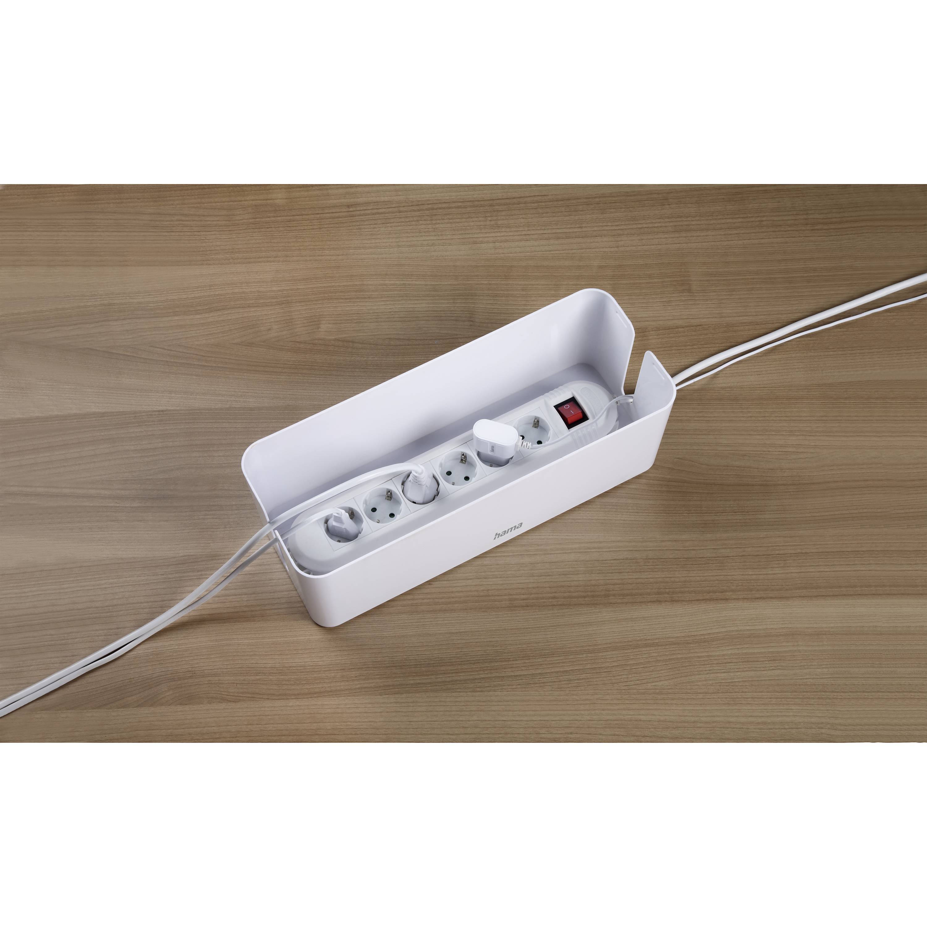 Eine weiße Kabelbox enthält eine Mehrfachsteckdose mit mehreren Steckdosen. Ein Schalter ist sichtbar. Box steht auf Holztisch.