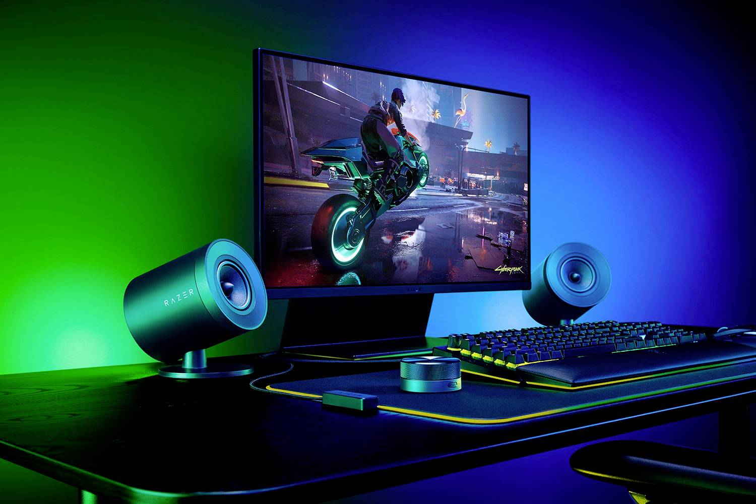 Ein Computerbildschirm zeigt ein futuristisches Spiel mit einem Motorrad. Ein Gaming-Setup mit Tastatur und Lautsprechern ist sichtbar.