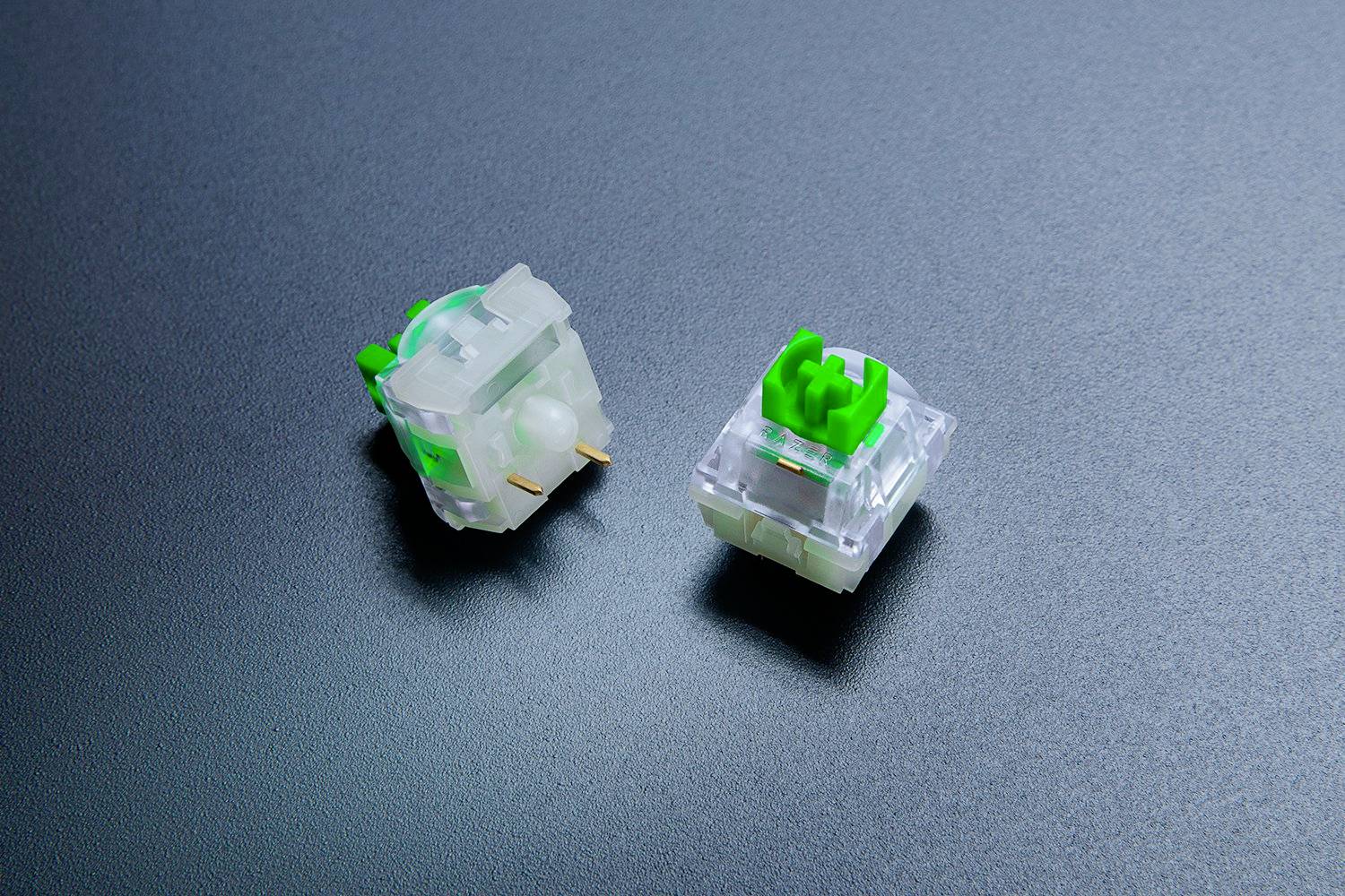 Zwei mechanische Tastaturschalter, einer liegend und einer stehend, auf einer glatten, dunklen Oberfläche.
