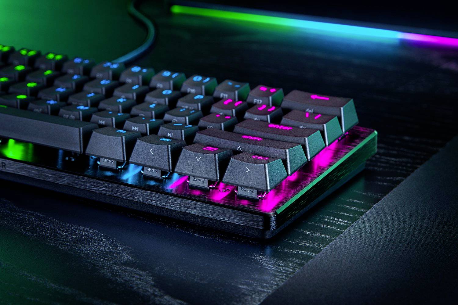 Gaming-Tastatur mit RGB-Beleuchtung auf einem Schreibtisch. Die Tasten leuchten in lebendigem Blau und Pink.