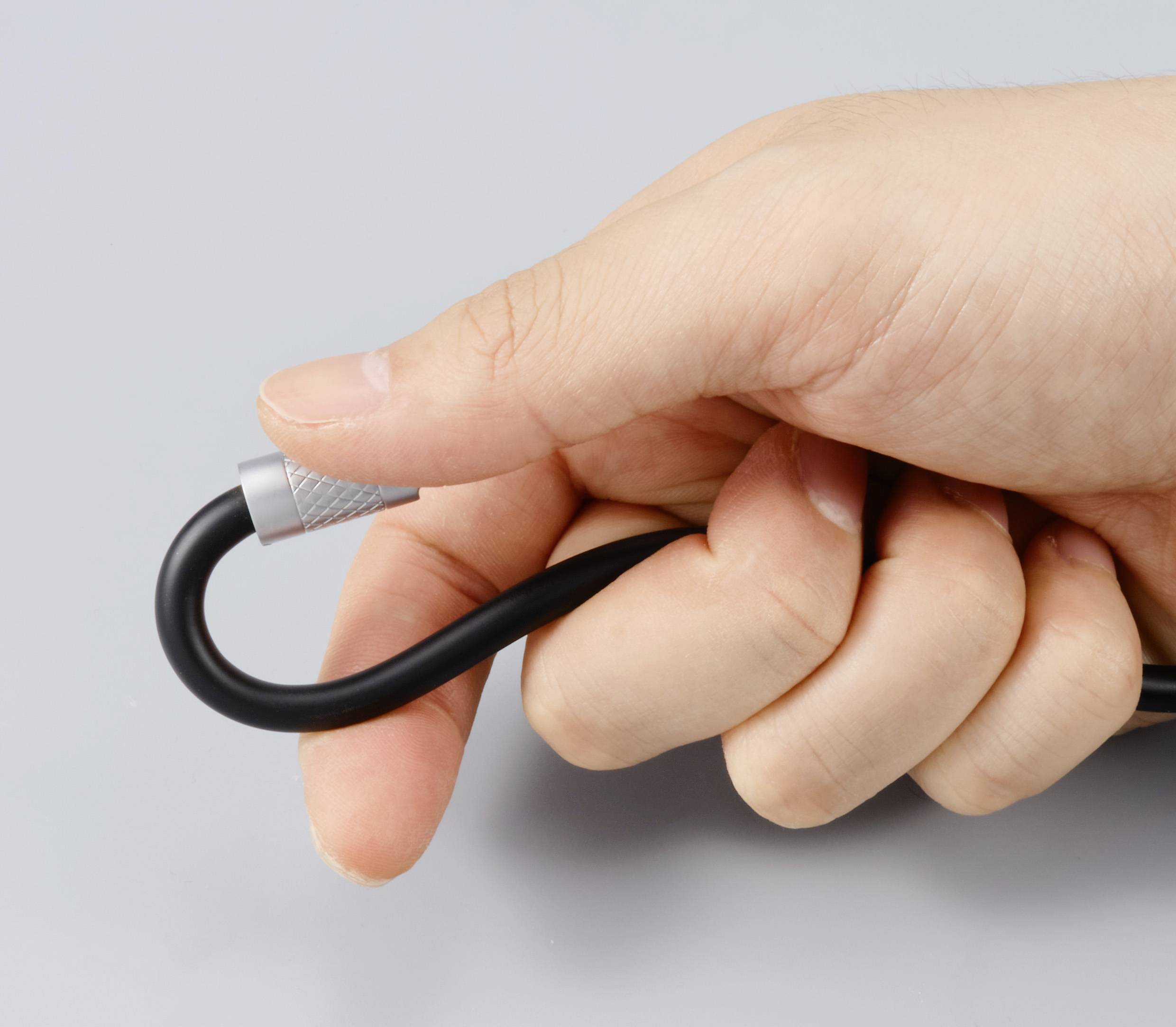 Eine Hand hält ein schwarzes Kabel, das in einer Schleife gebogen ist.