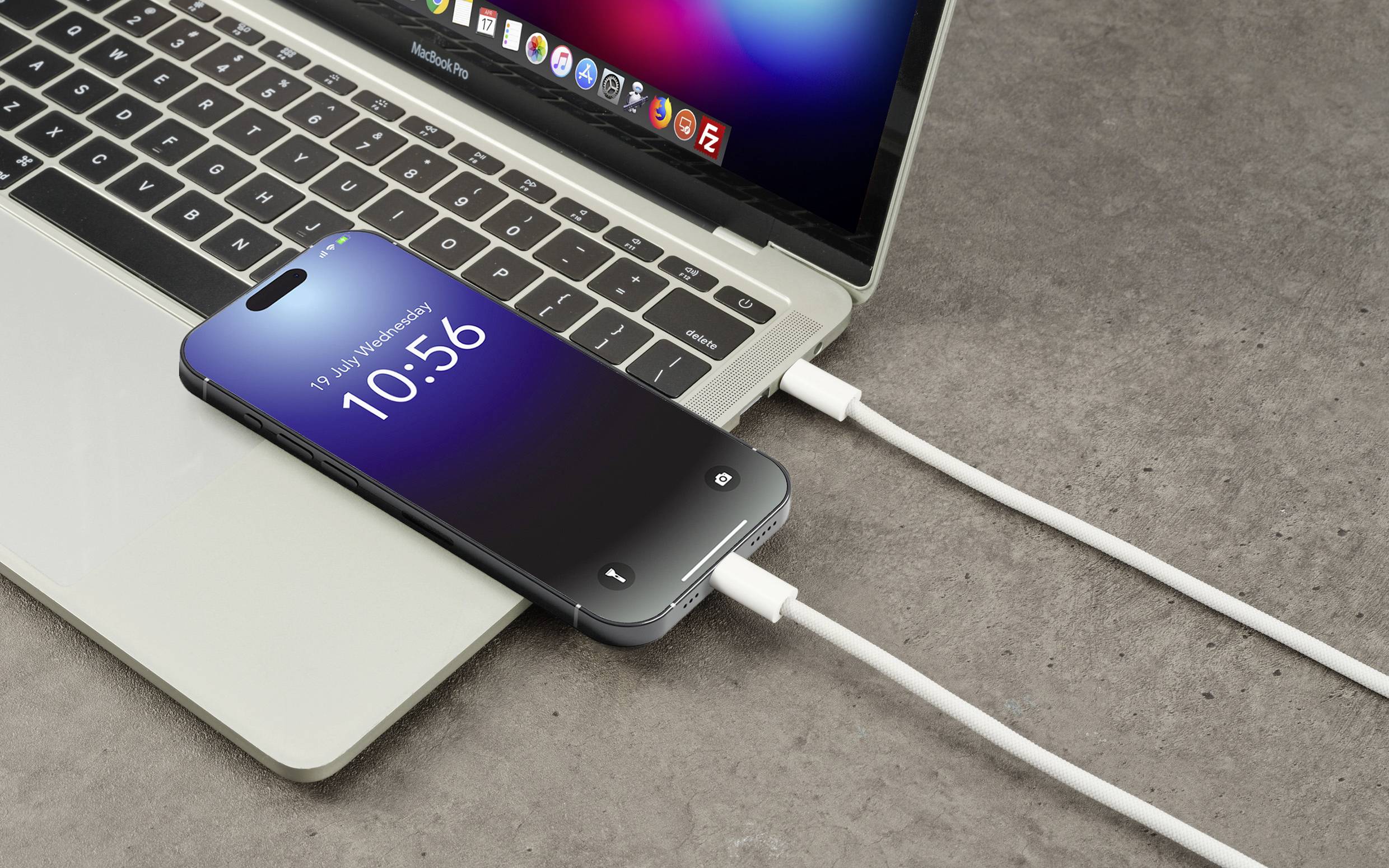 Smartphone liegt auf einem Laptop und wird per Kabel aufgeladen. Beide Geräte sind eingeschaltet. Zeit auf dem Smartphone-Display: 10:56.