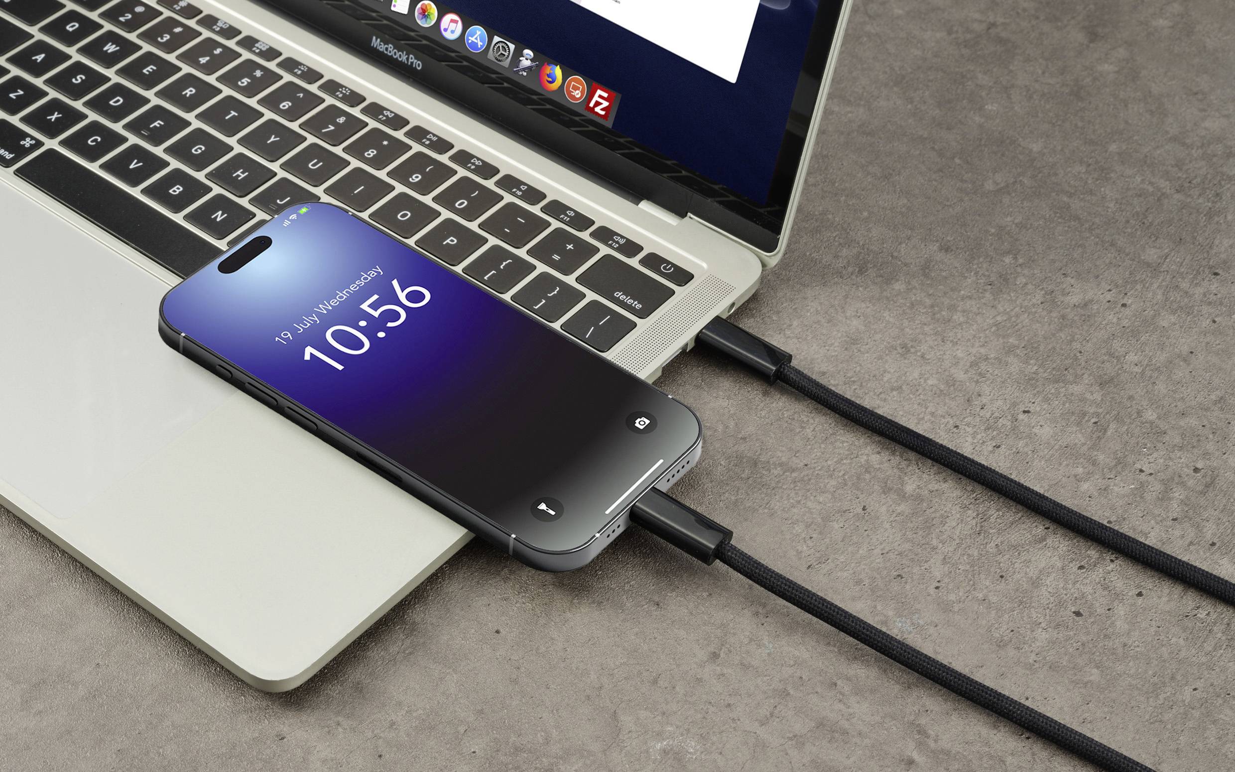 Ein Smartphone wird über ein schwarzes Kabel an ein geöffentlichtes Laptop angeschlossen. Auf dem Telefonbildschirm steht die Uhrzeit '10:56'.