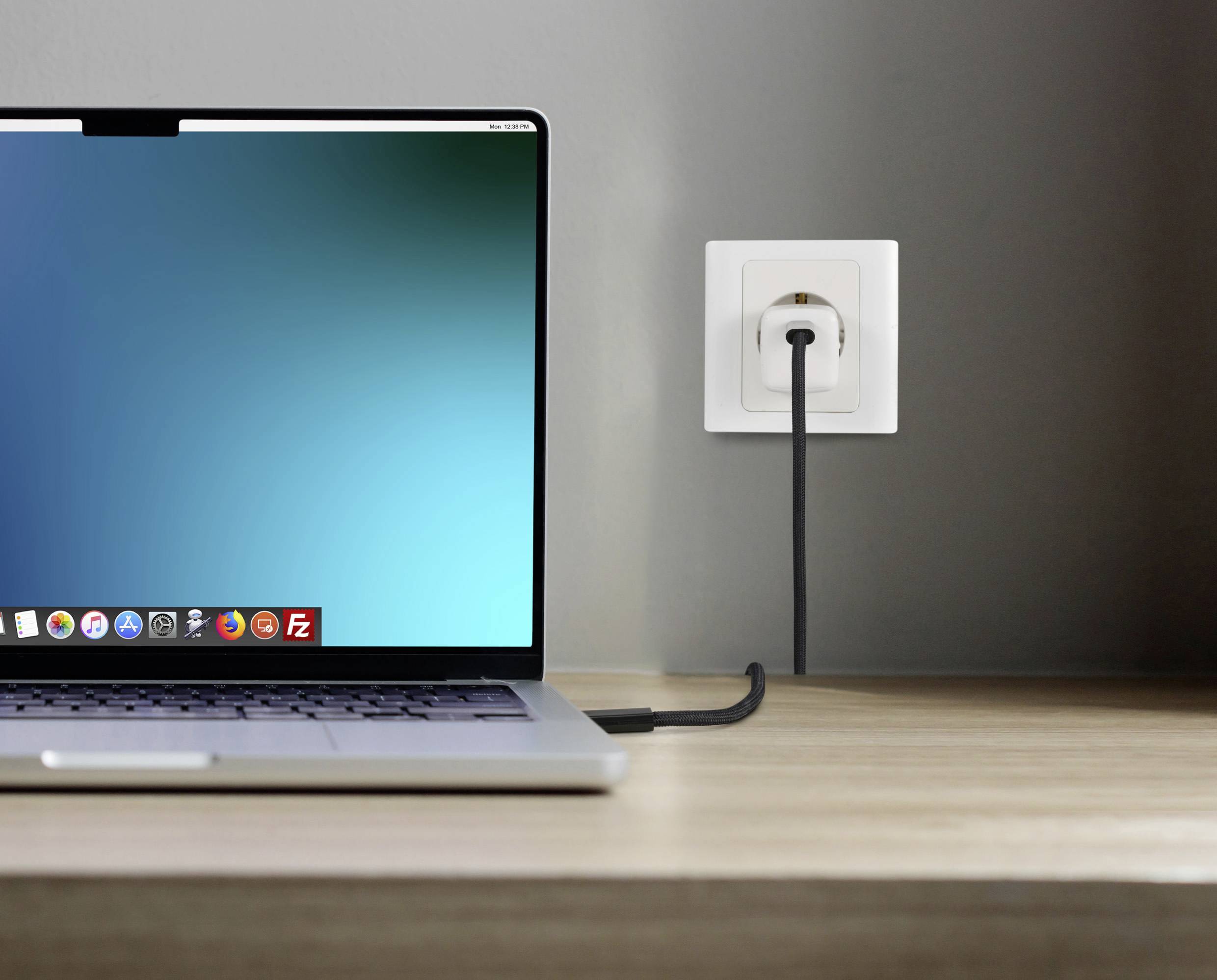 Ein Laptop ist an eine Wandsteckdose angeschlossen und steht auf einem Tisch. Der Bildschirm zeigt einen leeren, blauen Hintergrund.