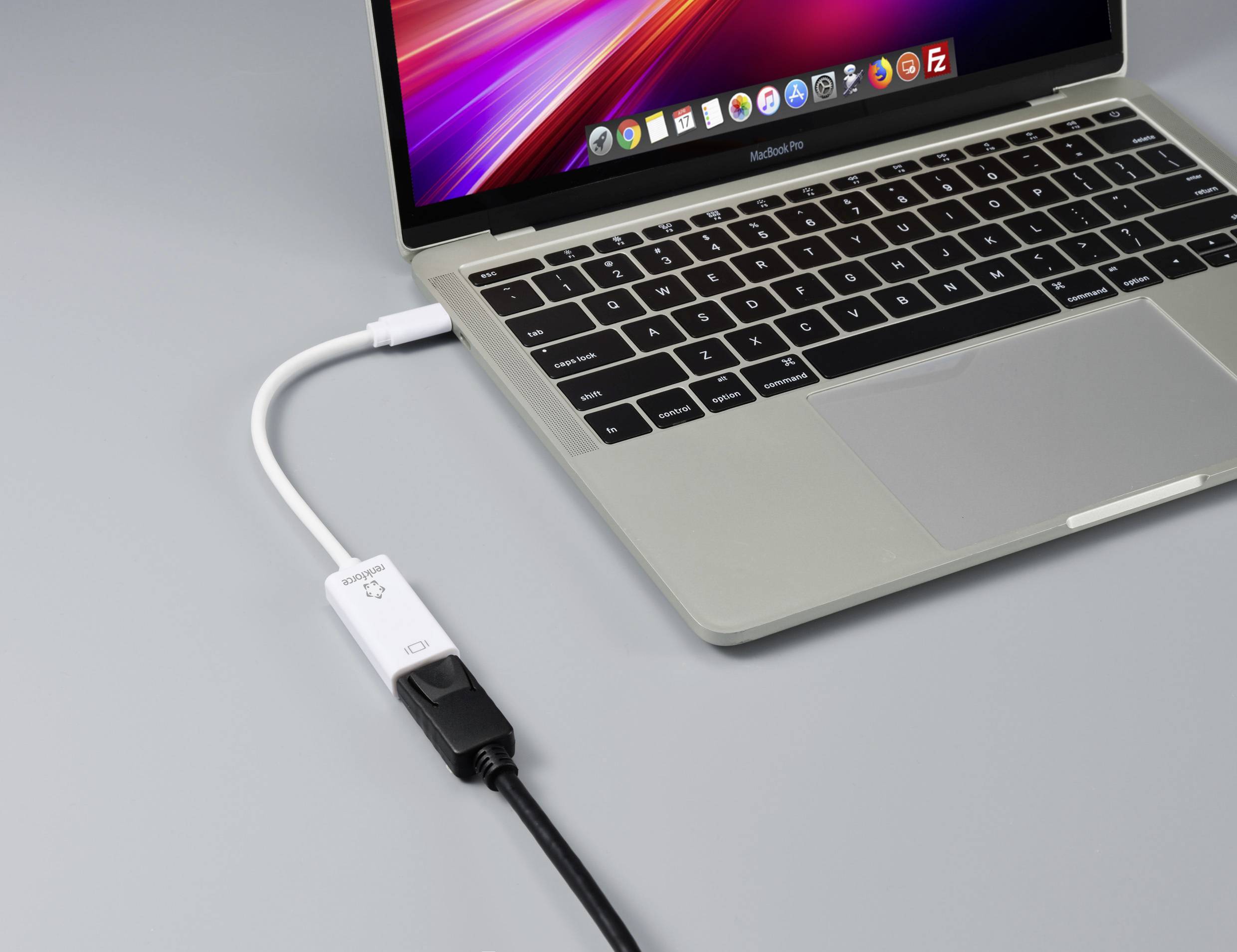 Ein Laptop ist über ein USB-Kabel mit einem Adapter verbunden. Das Display zeigt den Desktop an.