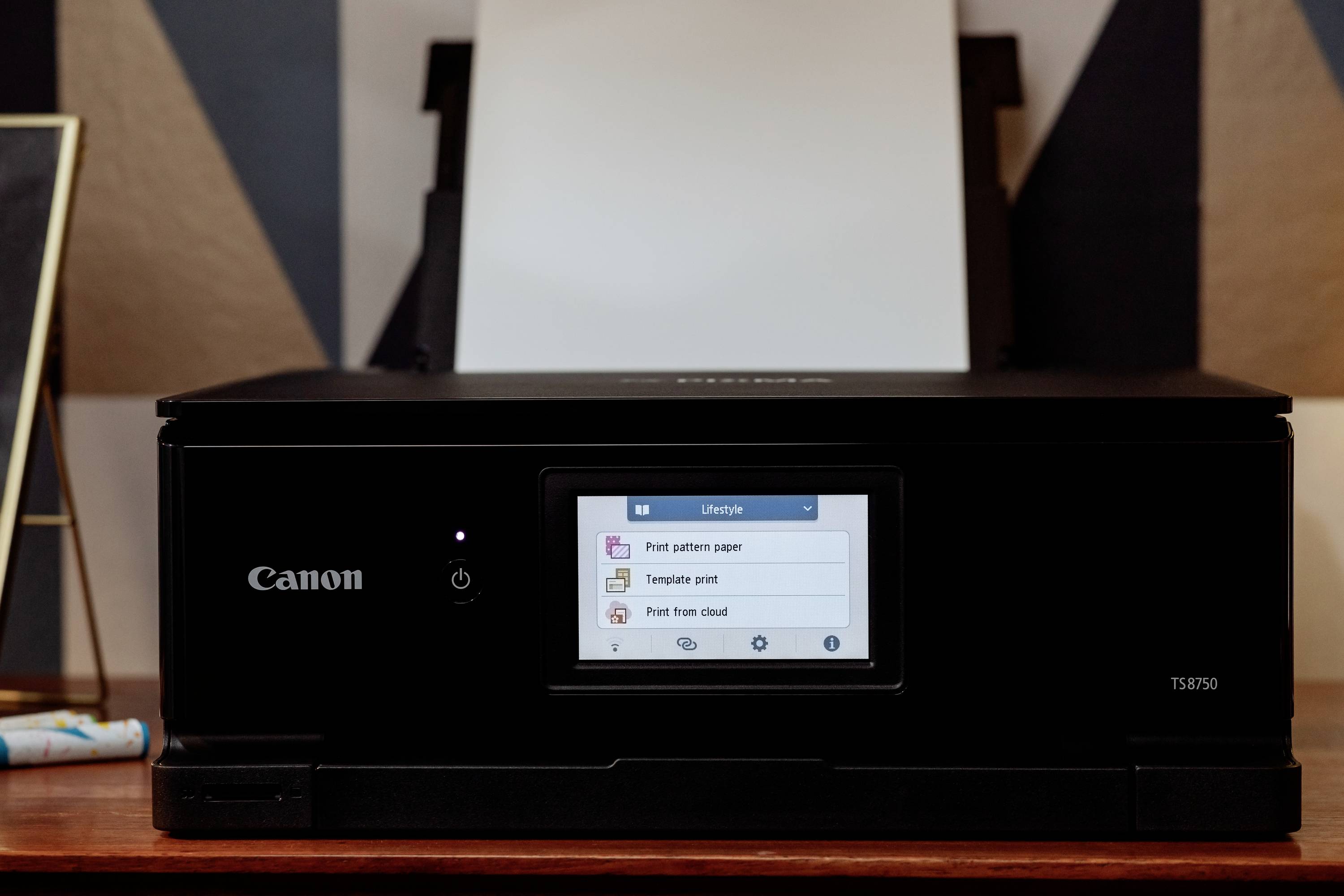 Ein Canon-Drucker steht auf einem Tisch, das Display zeigt 'Print pattern paper', 'Template print' und 'Print from cloud'.