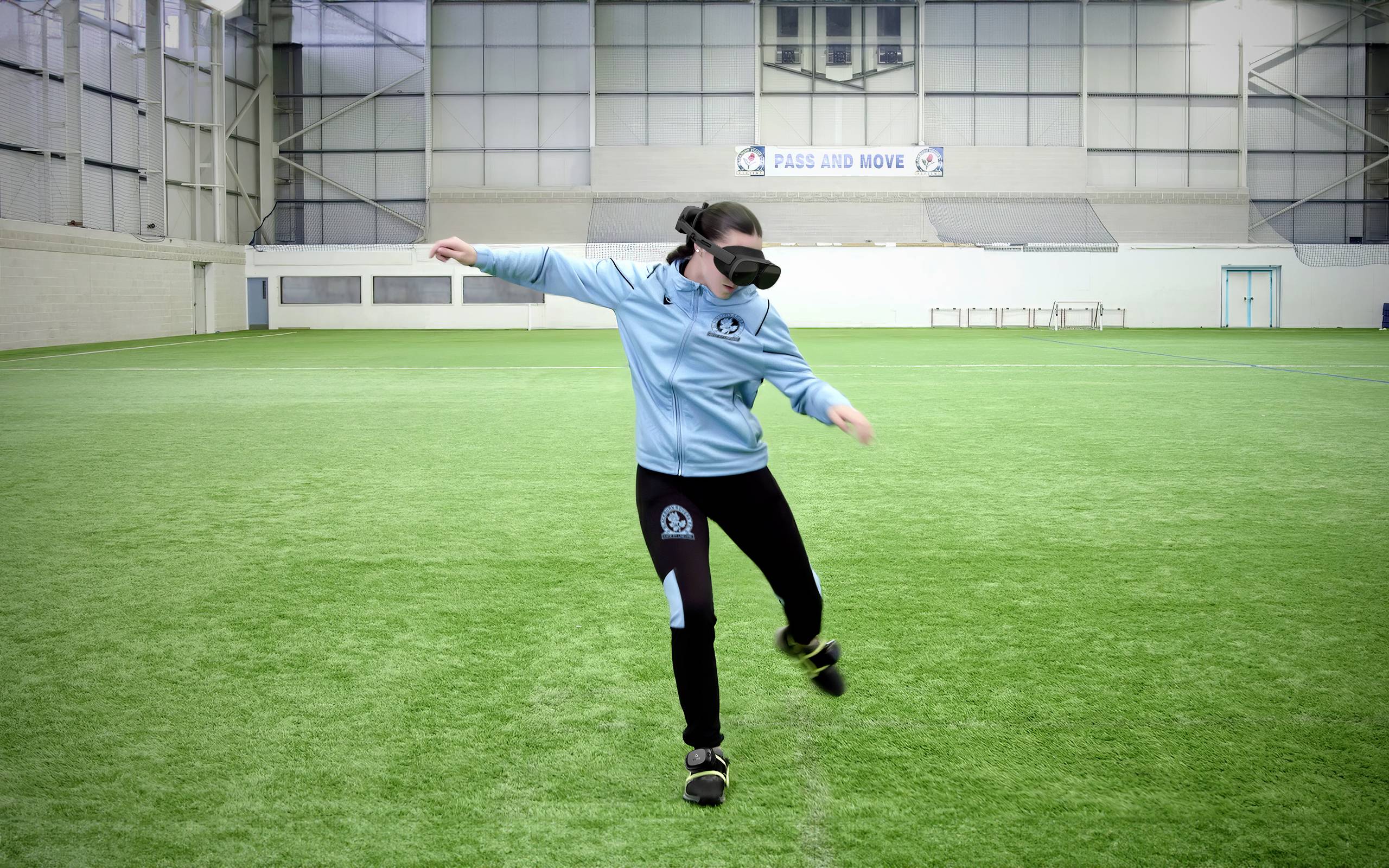 Eine Person auf einem grünen Sportplatz trägt Augenbinde und Sportbekleidung. Sie streckt die Arme aus und bewegt sich vorsichtig.