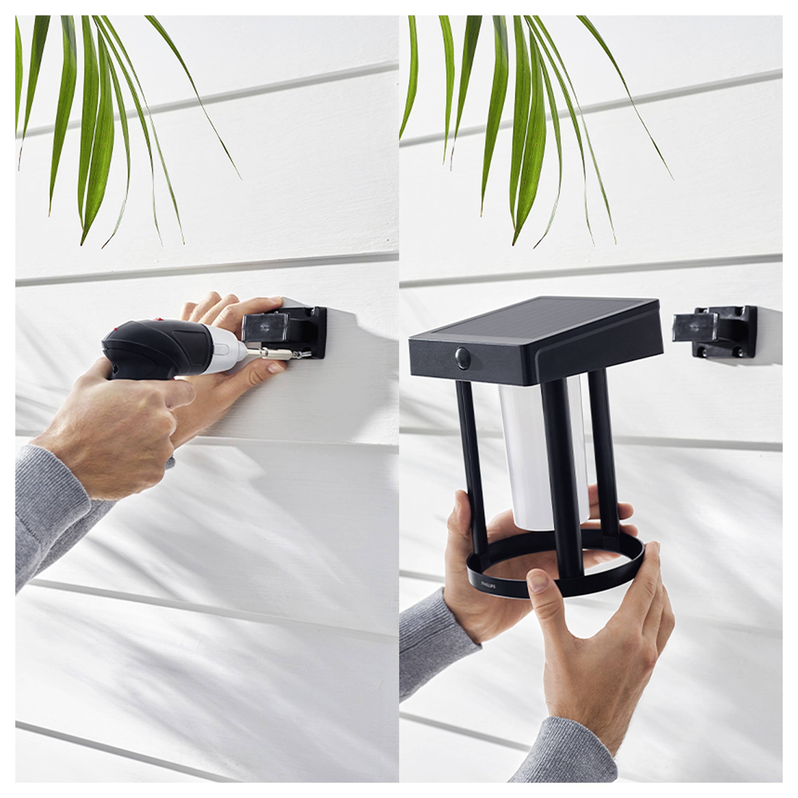 Eine Person montiert eine schwarze Solarwandleuchte mit einem Bohrer an einer weißen Wandverkleidung und zeigt dann die fertig installierte Leuchte im Freien.