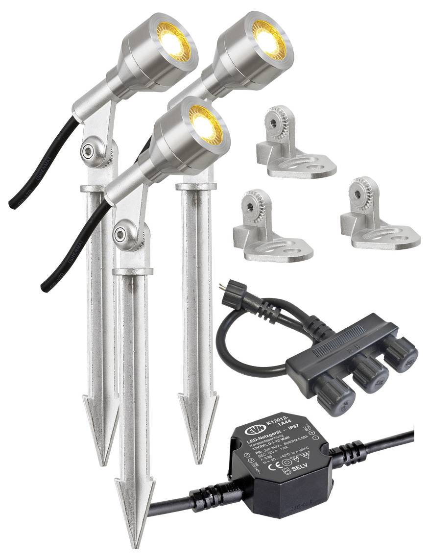 Drei Metallboden-Strahler mit Erdungsspießen, Montageklammern, Stromstecker und Transformator auf weißem Hintergrund dargestellt.